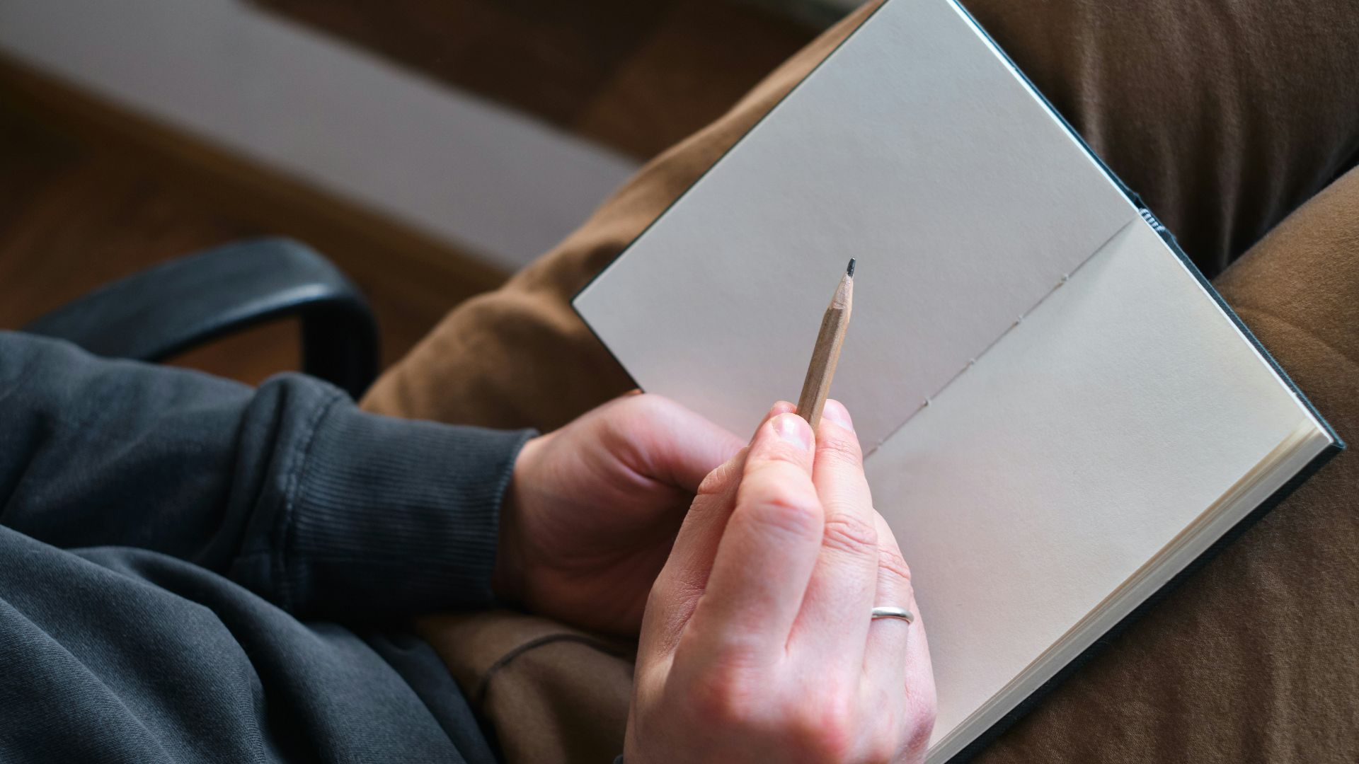 Person holding pencil over open notebook