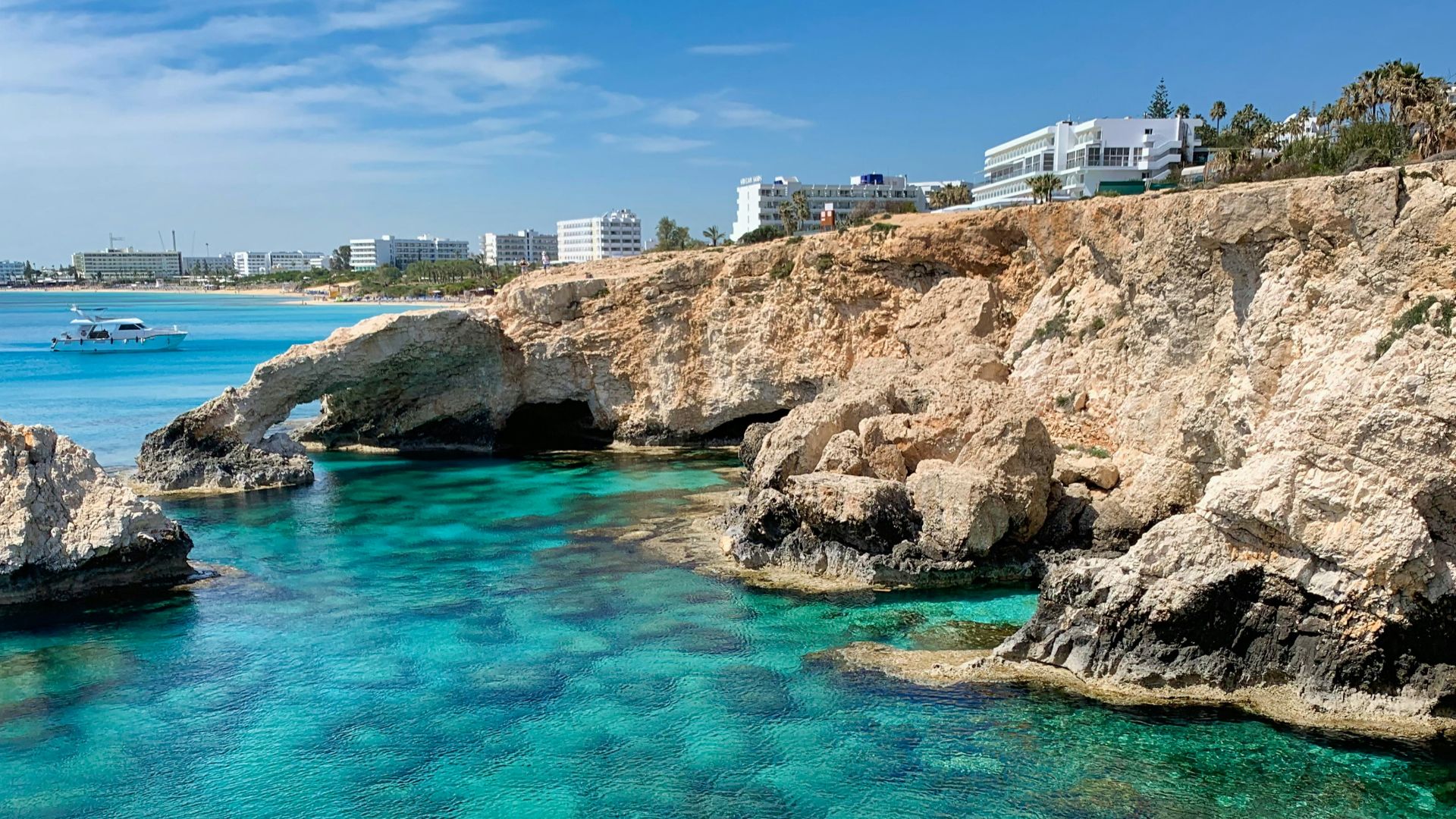 white concrete building on brown rock formation near body of water during daytime