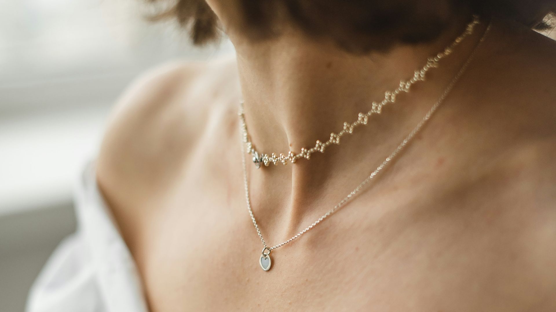 woman in white off shoulder shirt wearing silver necklace