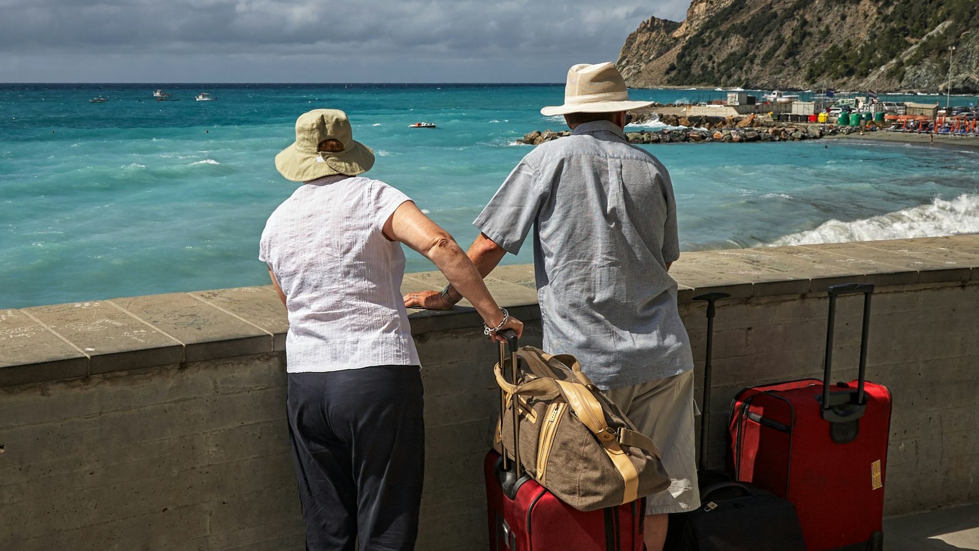 man and woman standing beside concrete seawall looking at beach