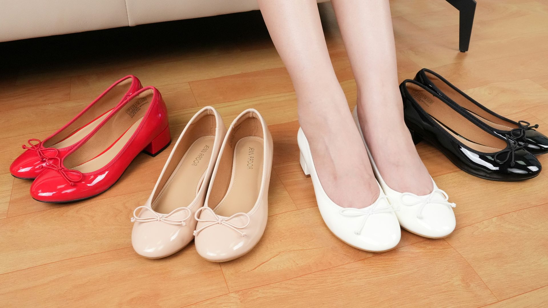 A woman sitting on a couch next to three pairs of shoes