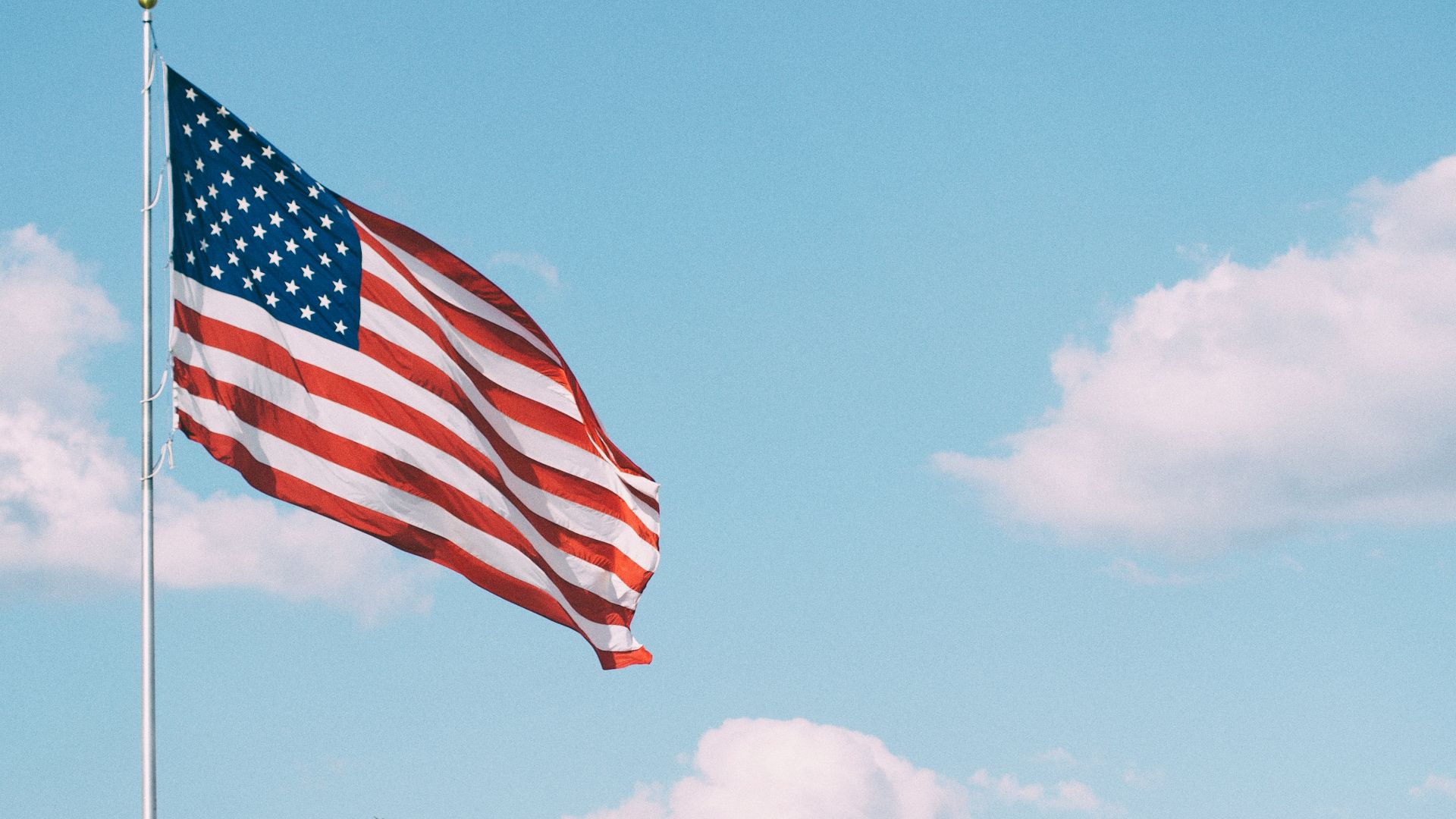 flag of U.S.A. under white clouds during daytime