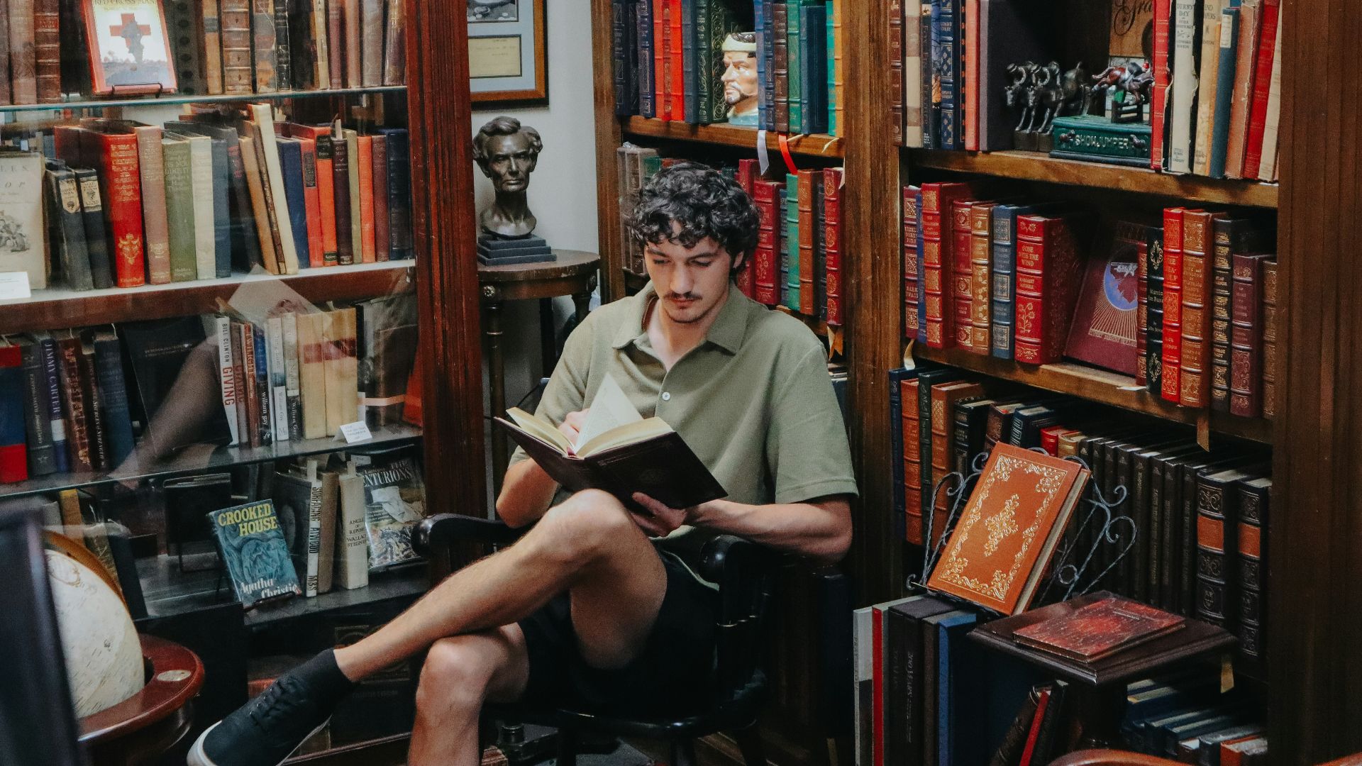A man reads a book in a cozy bookstore.