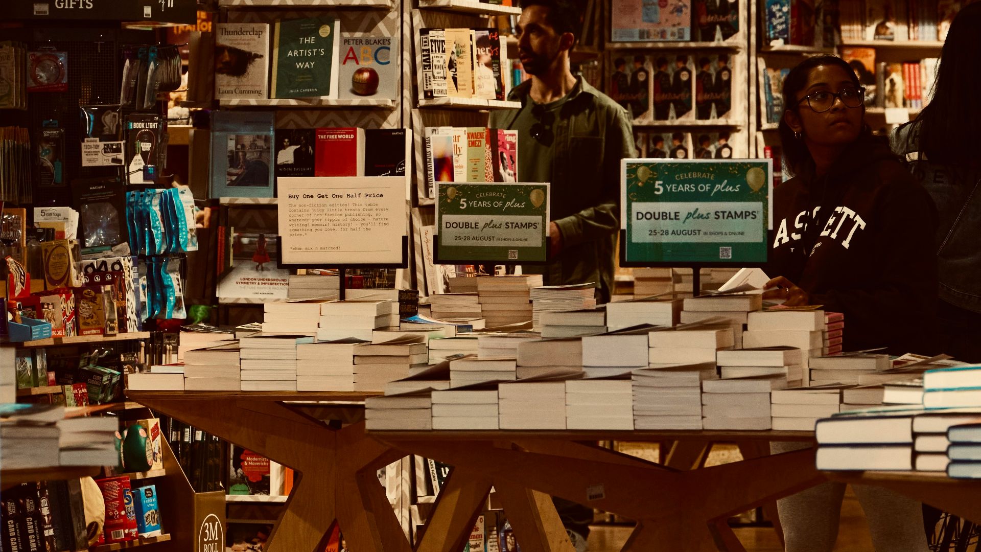 a woman standing in front of a table filled with books