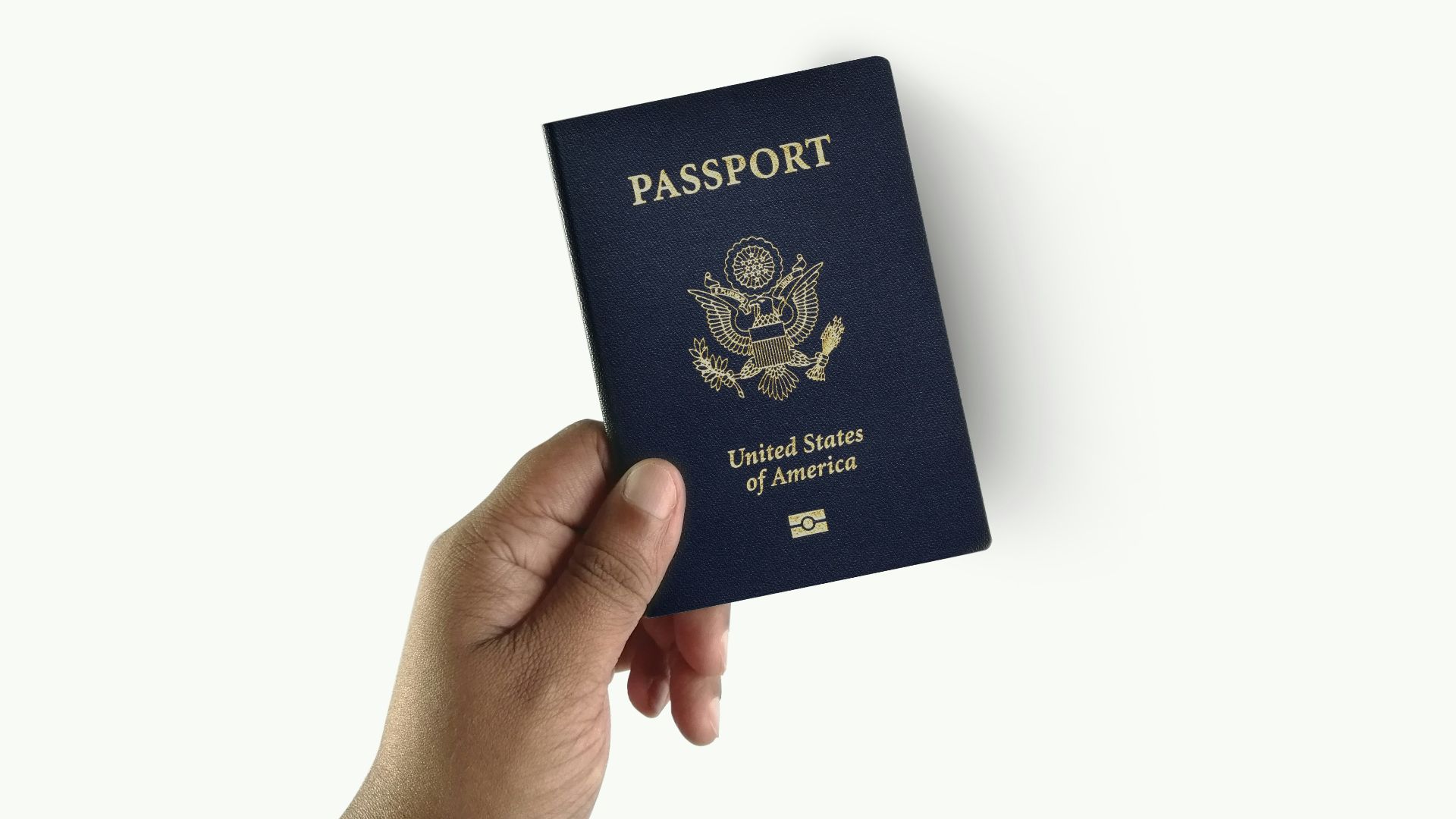 a hand holding a passport over a white background