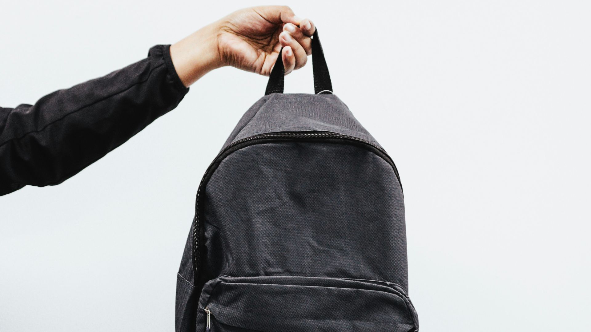 person in black jacket holding black backpack