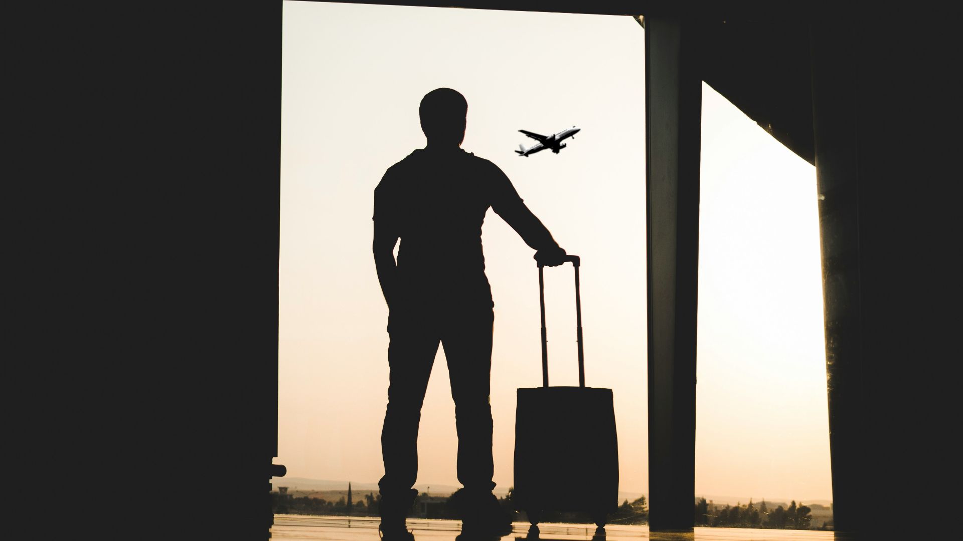 silhouette of man holding luggage inside airport