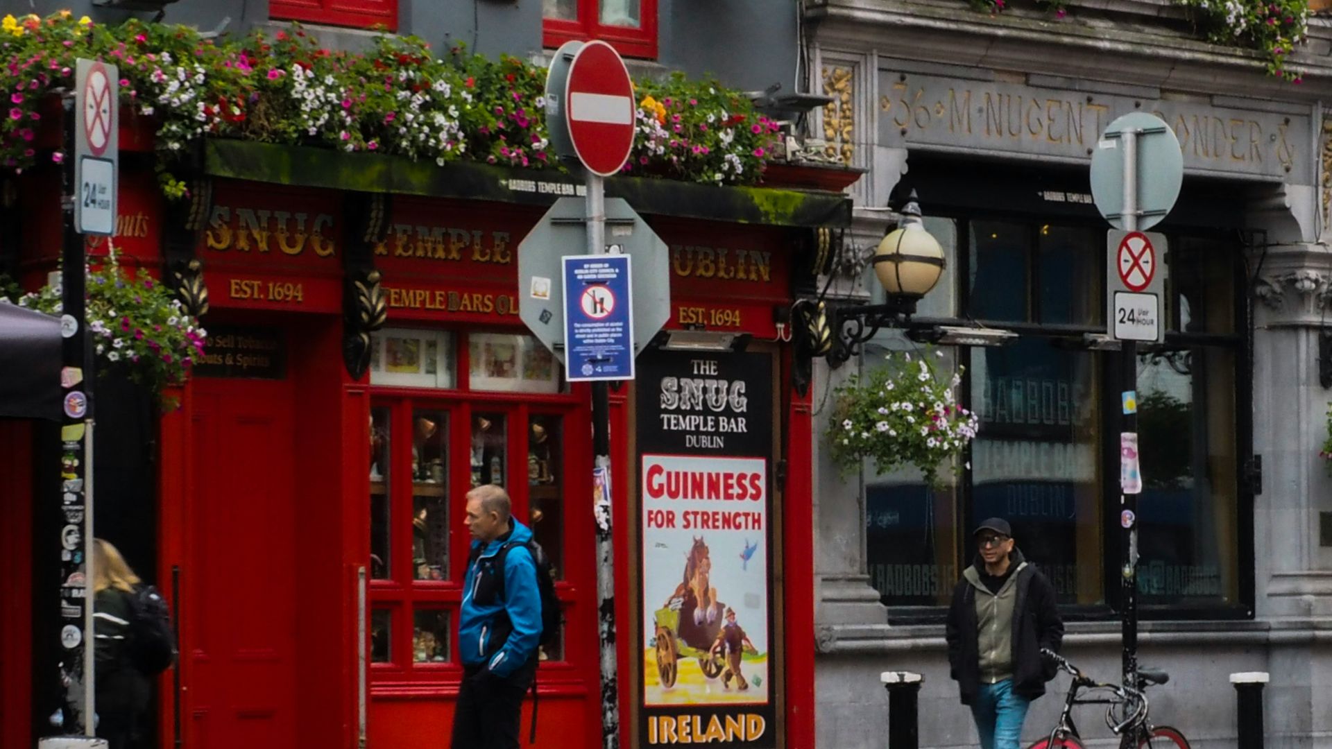 a couple of people standing in front of a building with a sign