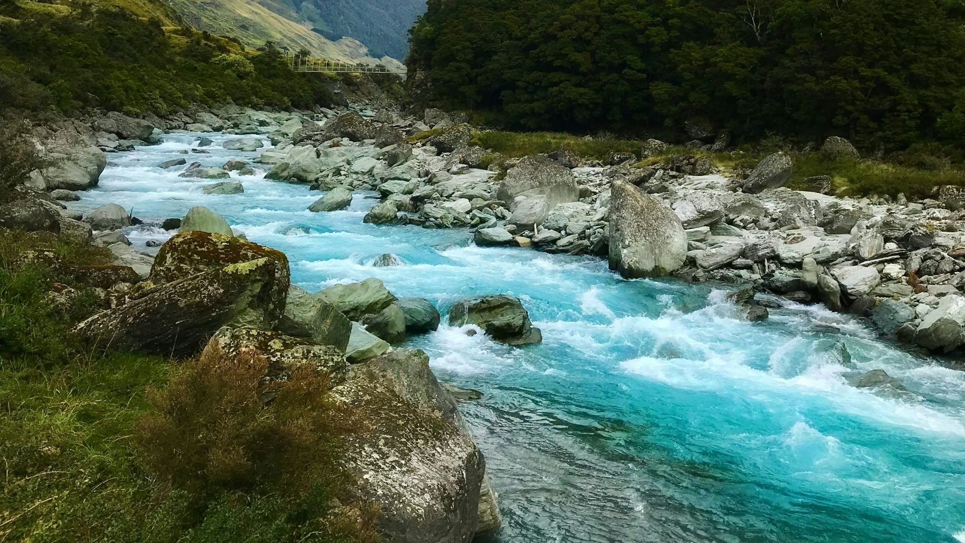 flowing river near green mountain under white clouds