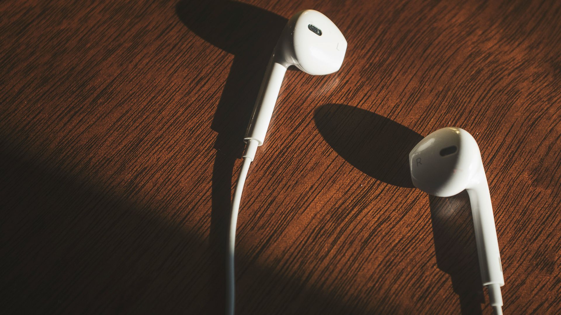 white earbuds on brown wooden table