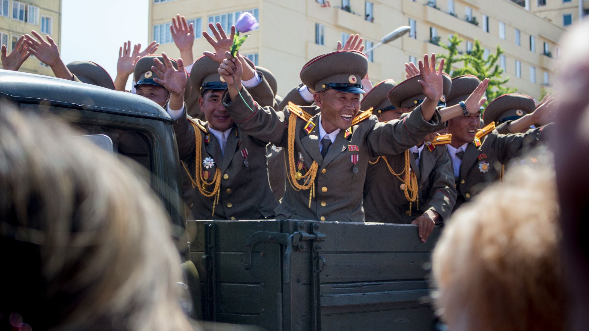 people in green and brown uniform standing near white concrete building during daytime