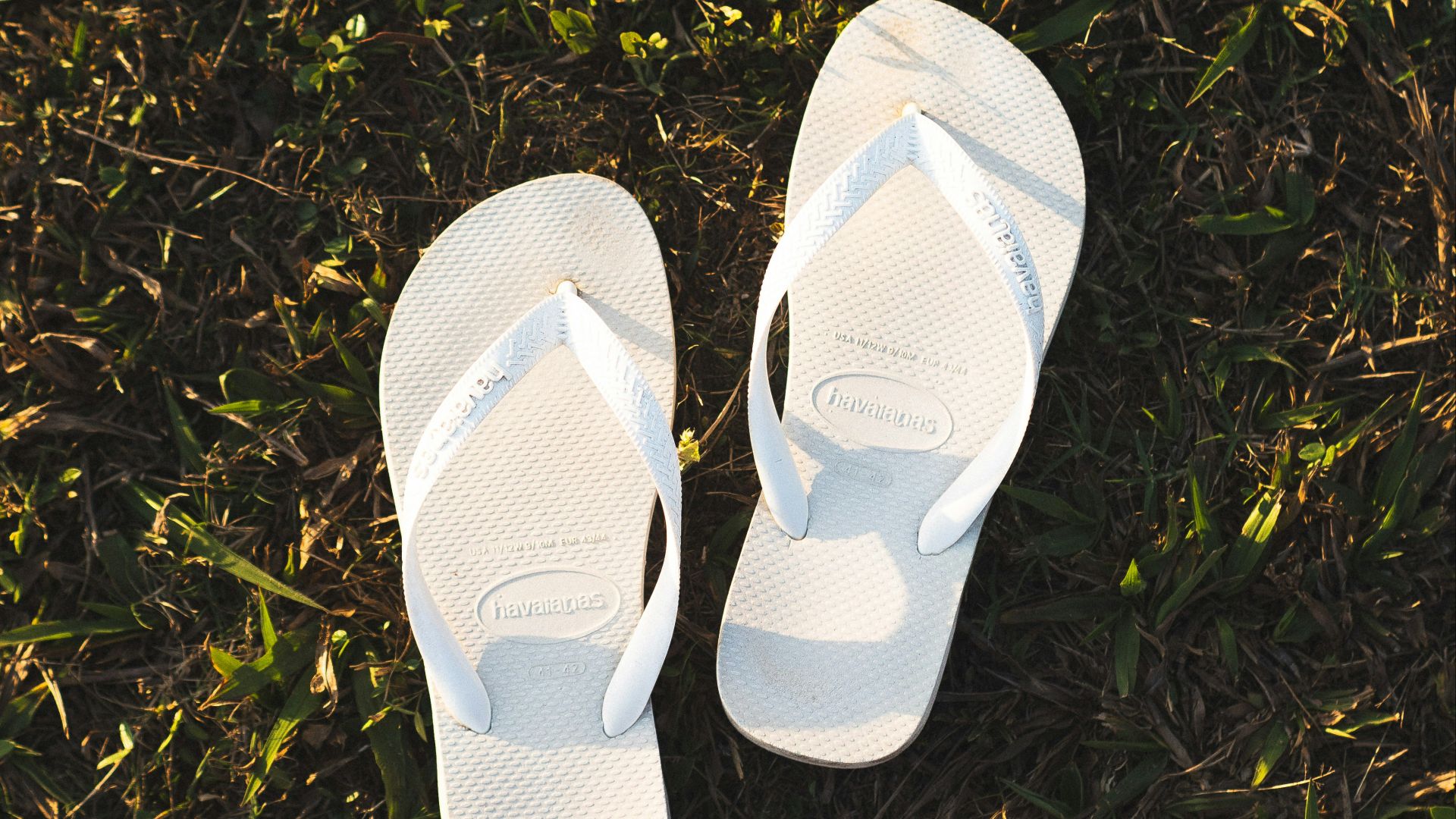 a pair of white slippers sitting on top of a lush green field