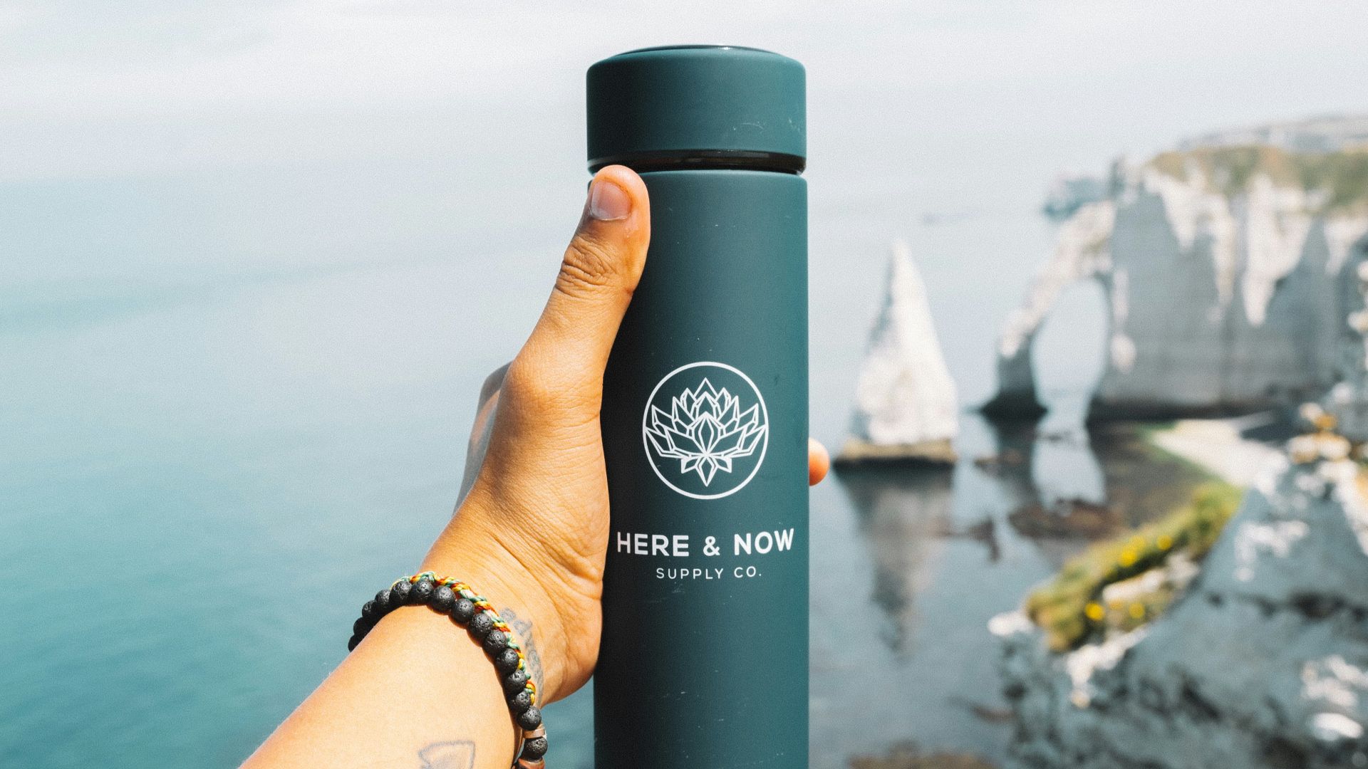 a person holding a water bottle in front of a body of water