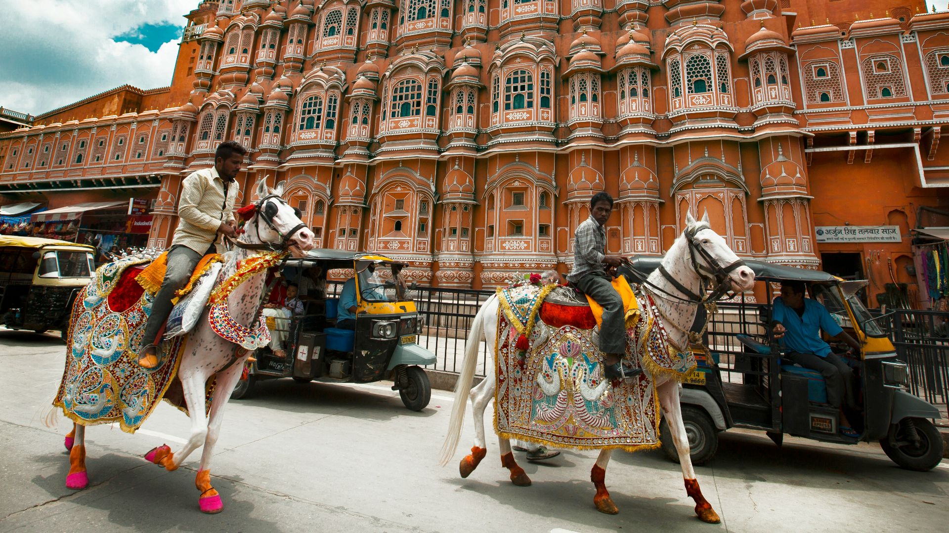 man in white and green long sleeve shirt standing near brown concrete building during daytime