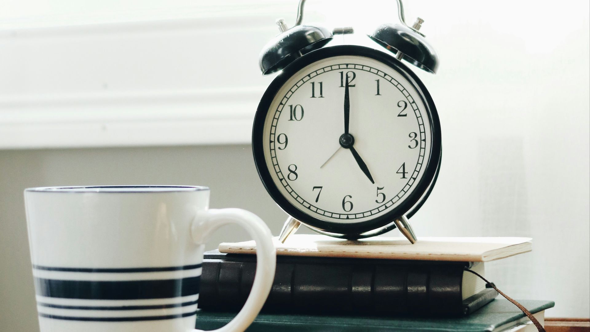 white ceramic mug beside white and black analog alarm clock