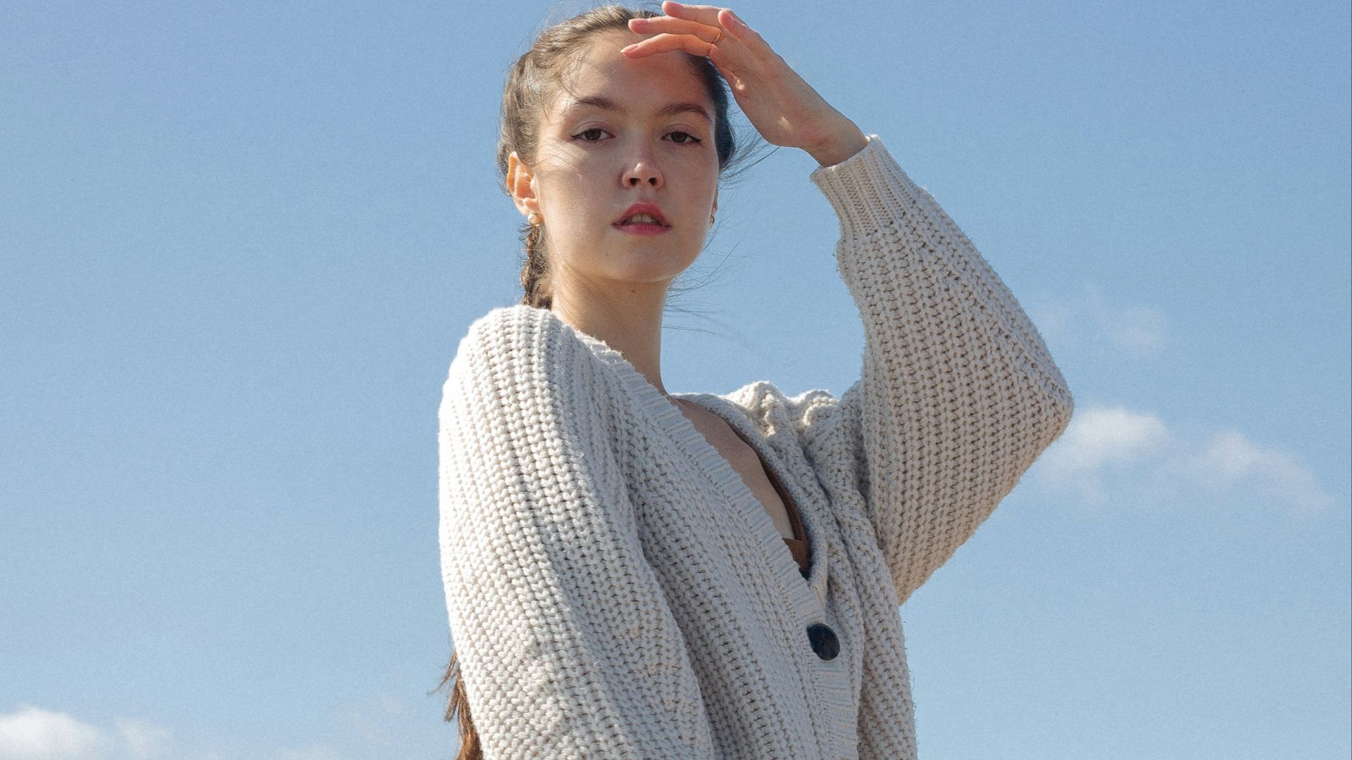 woman in white knit sweater and brown shorts standing under blue sky during daytime
