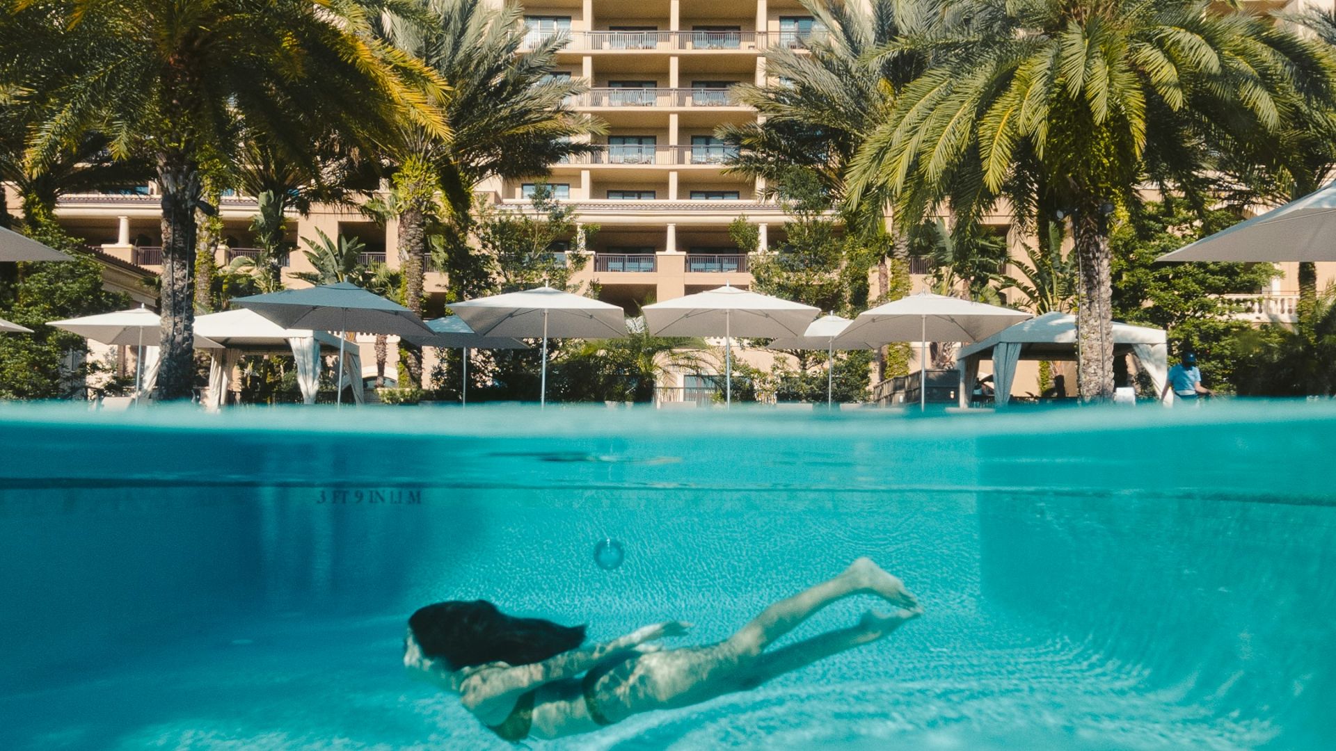 a woman swimming in a pool in front of a hotel