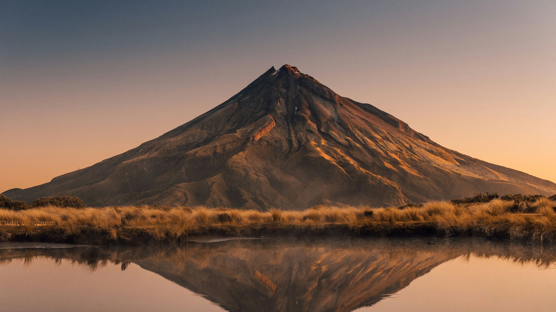 brown mountain near body of water during daytime