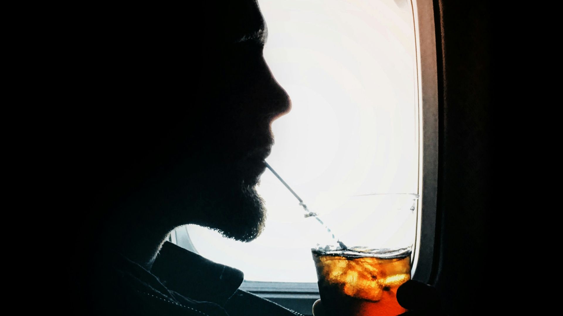 man sipping drink beside window