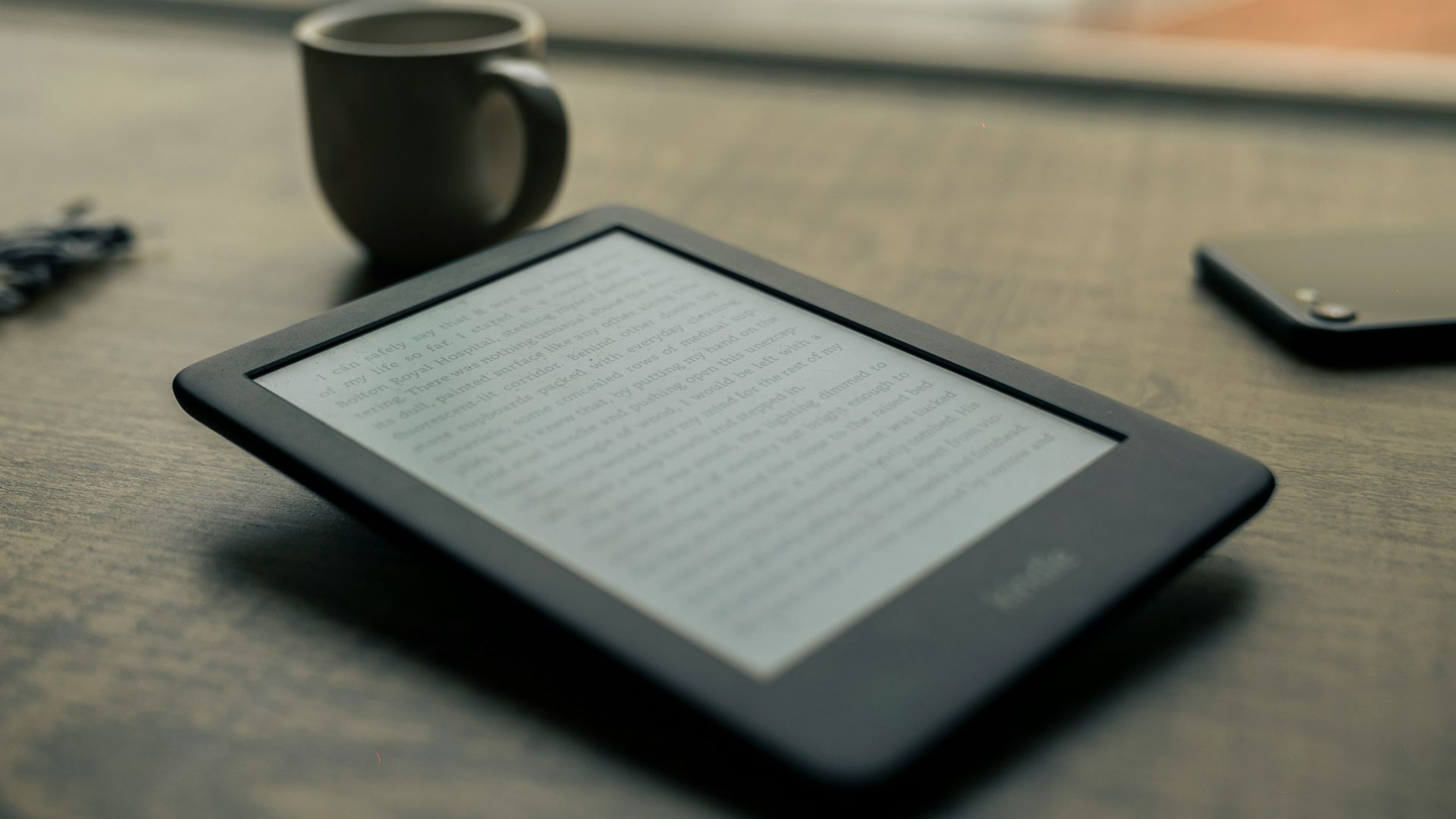 black android smartphone beside black ceramic mug on brown wooden table