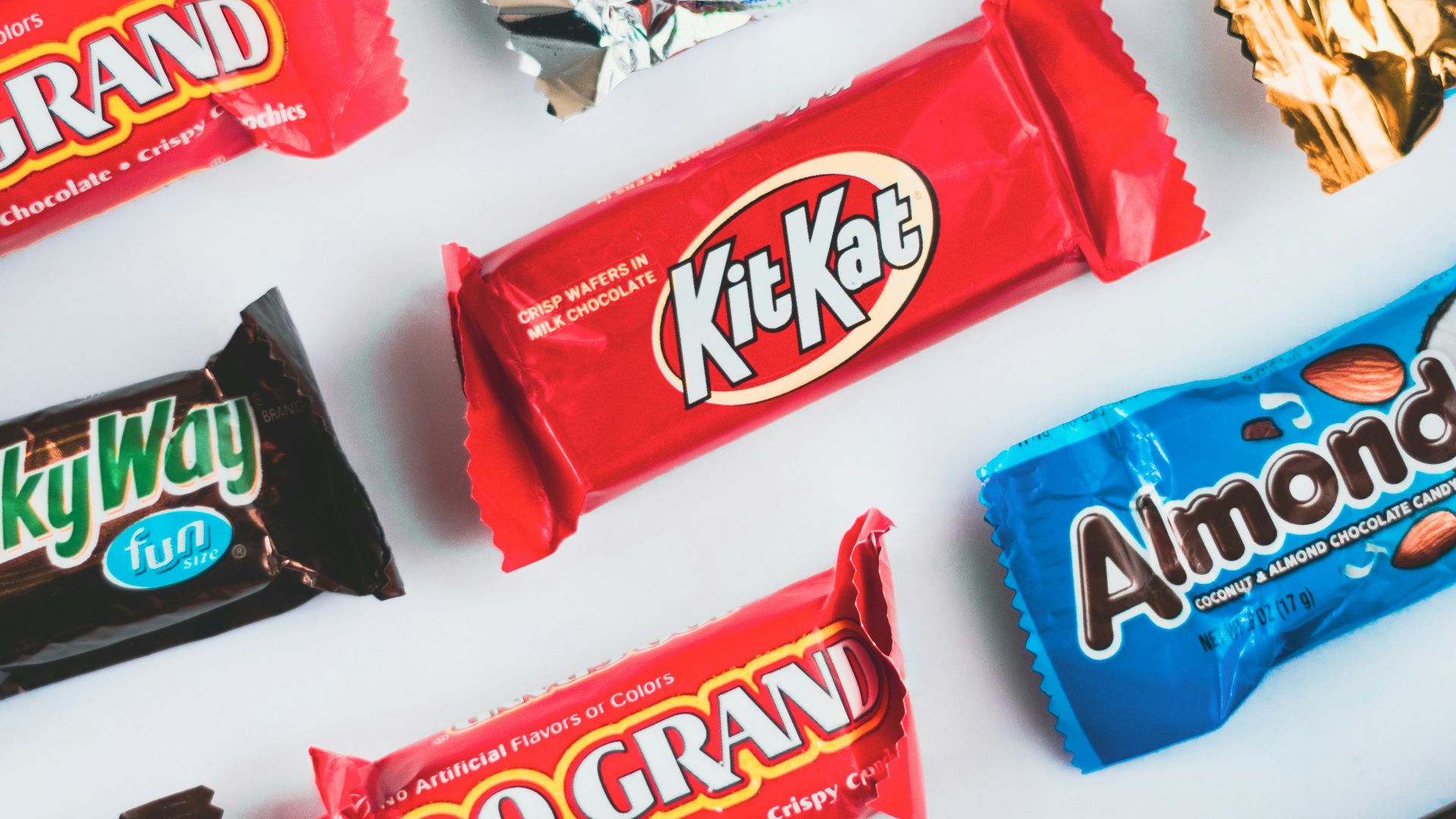 a variety of candy bars lined up on a white surface