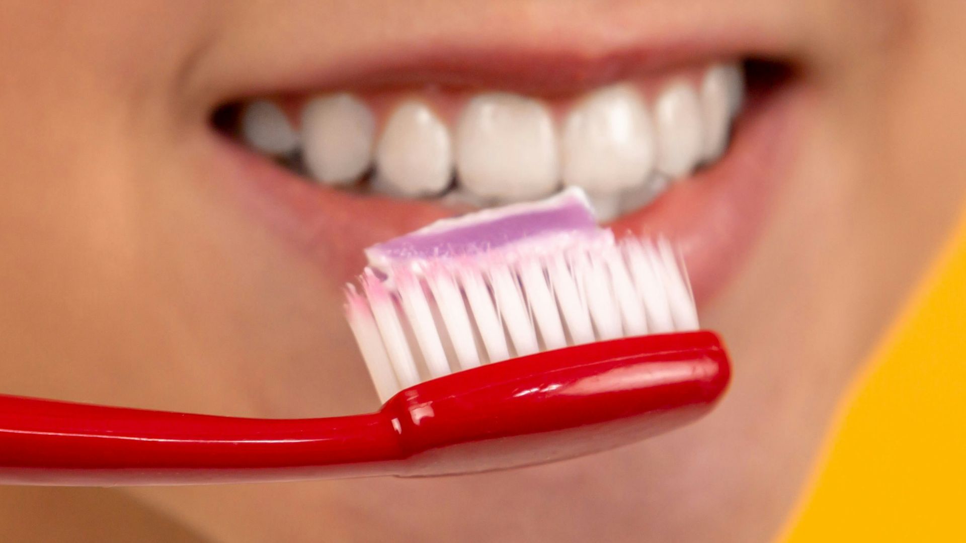 girl with red and white toothbrush in mouth