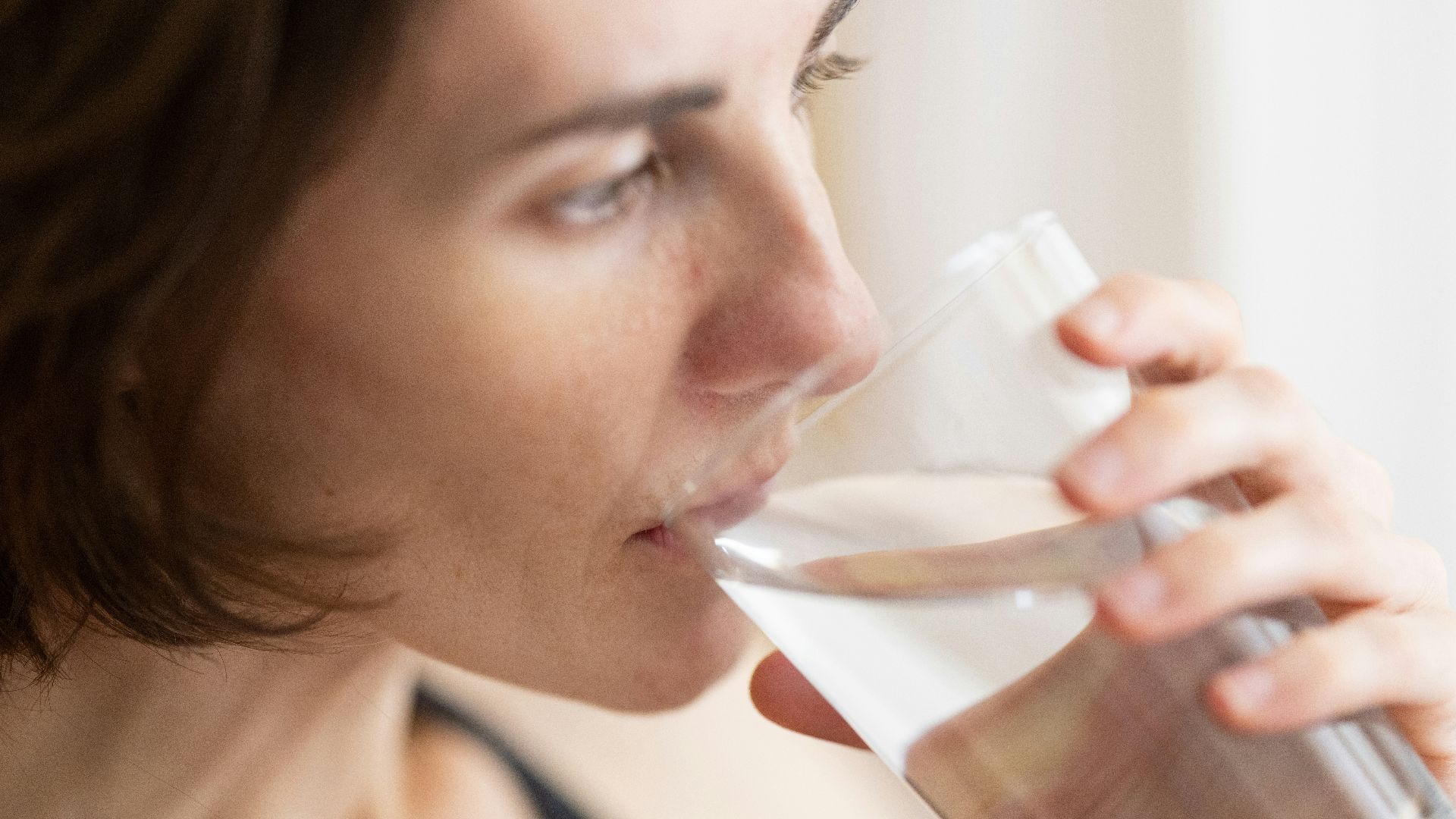 woman in black tank top drinking water