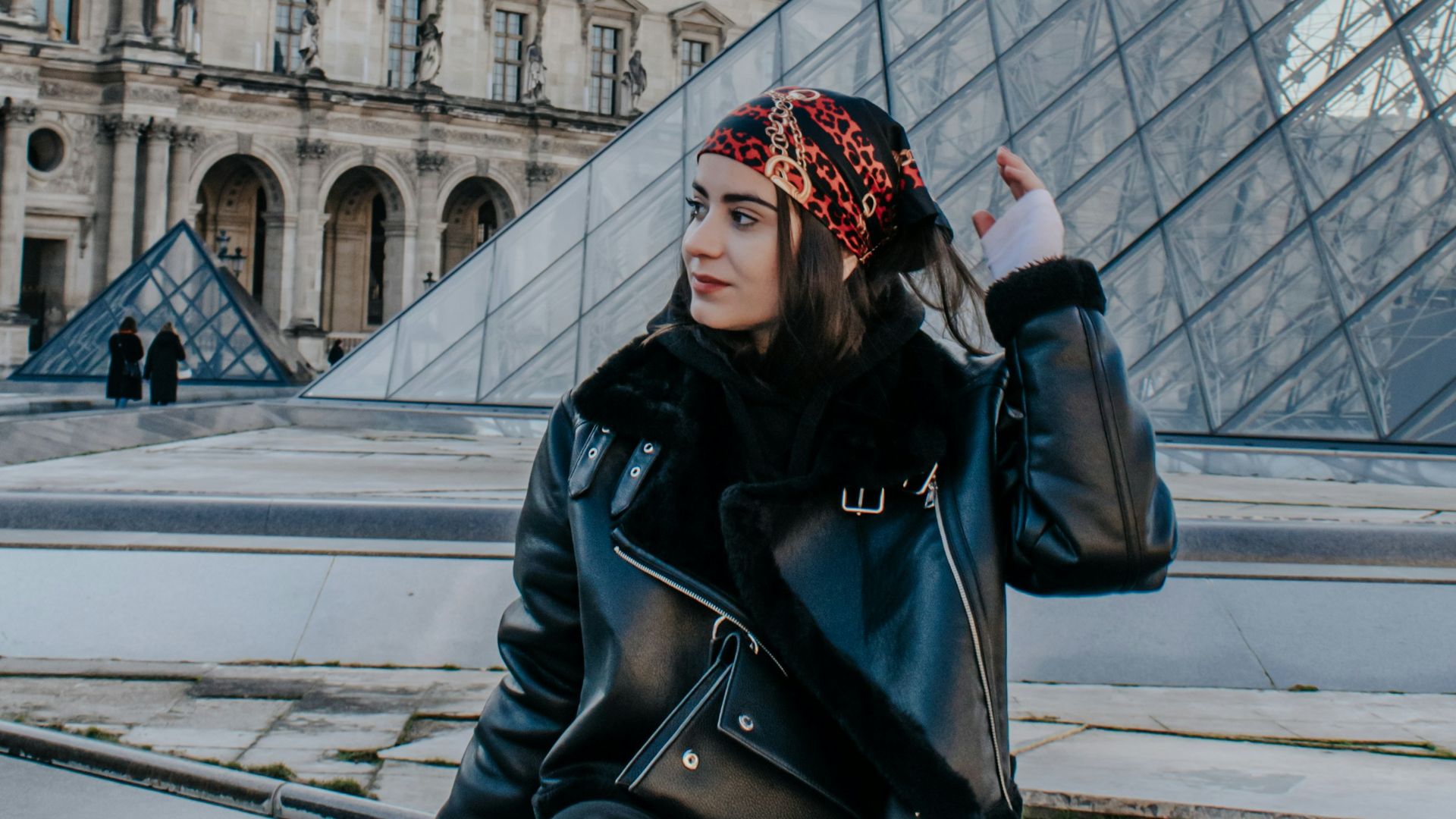 a woman sitting on a ledge in front of a building