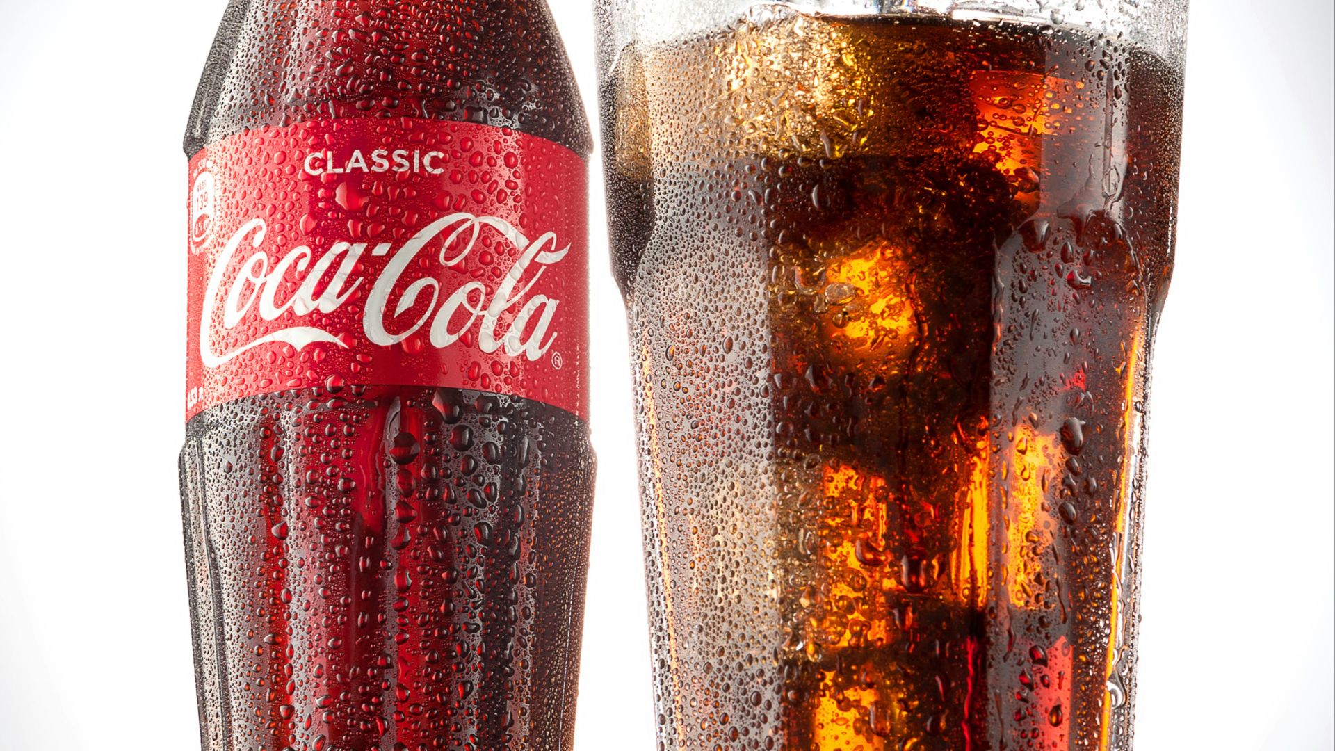 coca cola bottle beside drinking glass