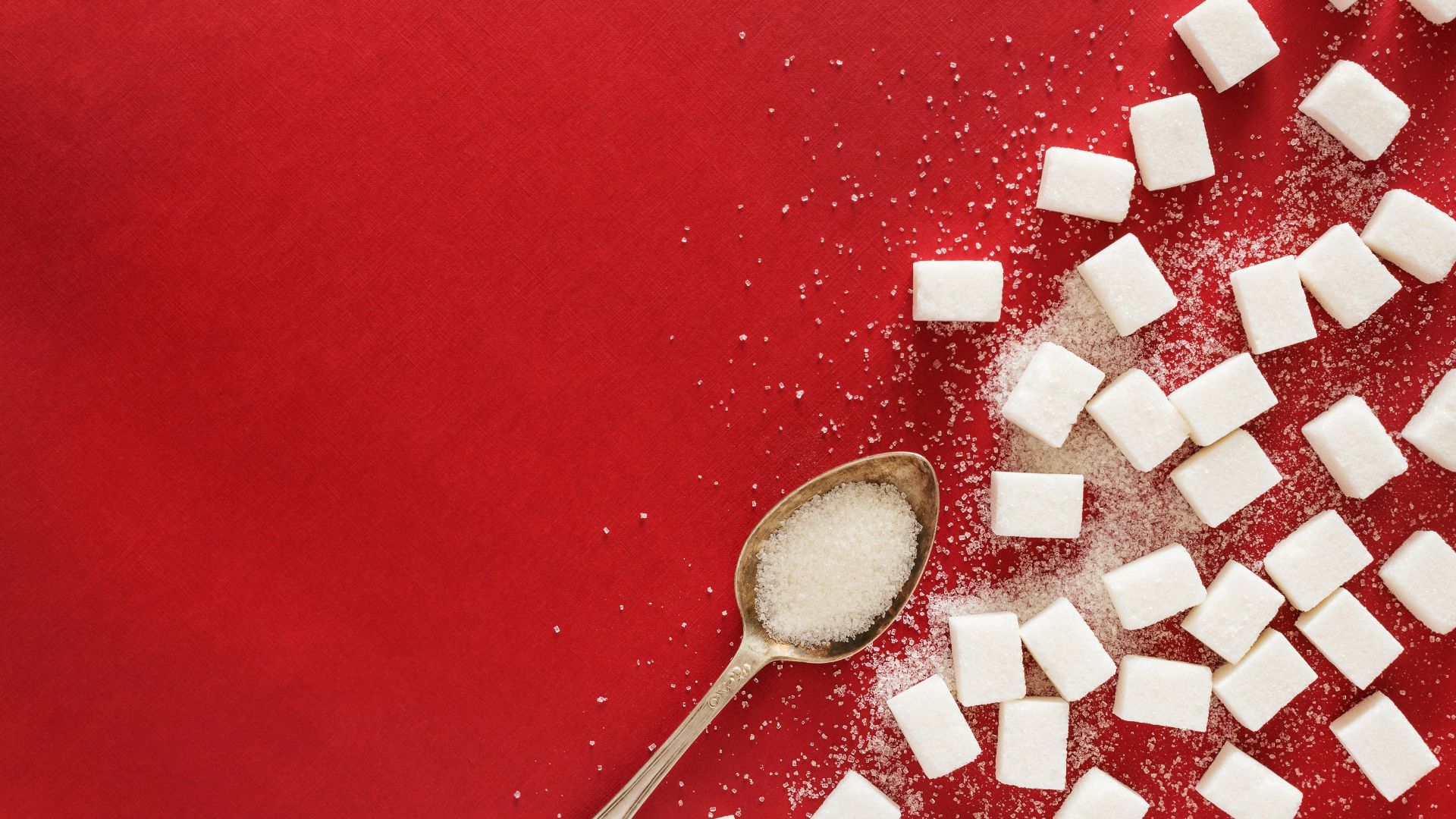 sugar cubes and a spoon on a red surface