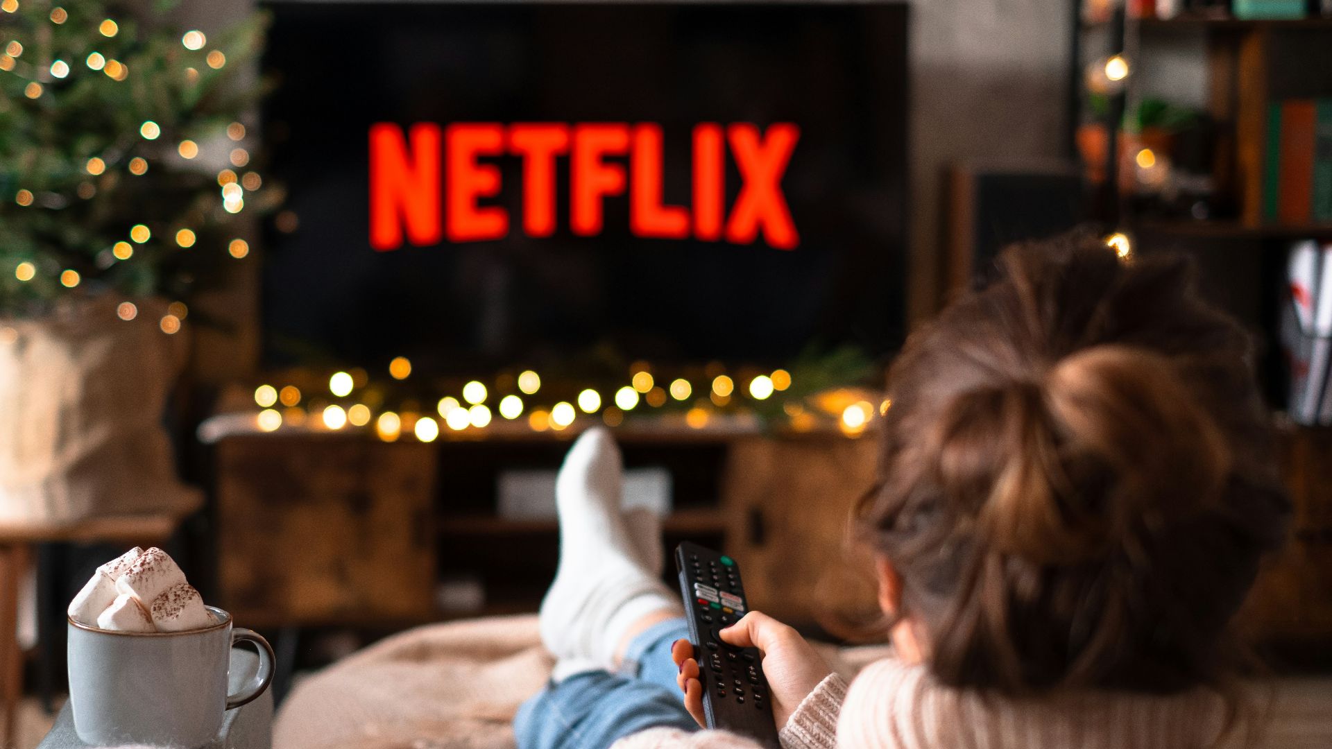 a little girl sitting on a couch watching tv