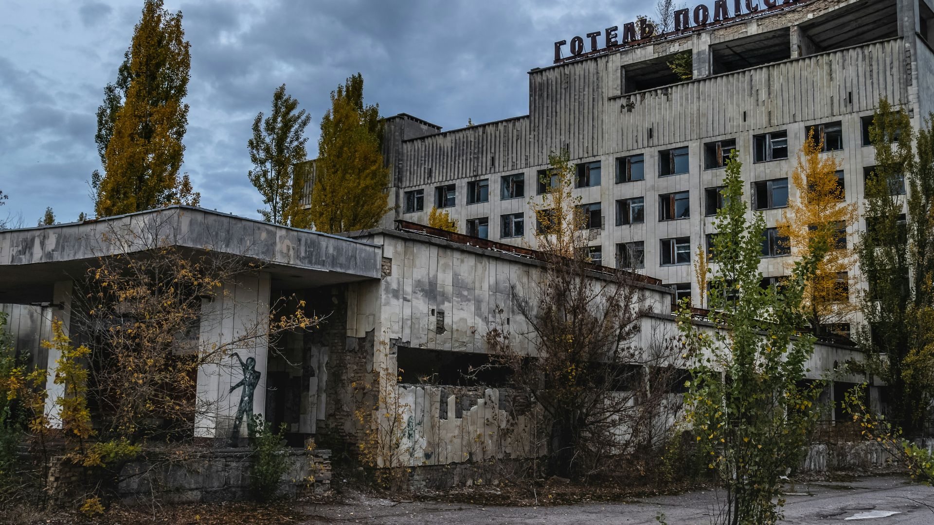 white concrete building near green trees under white clouds during daytime