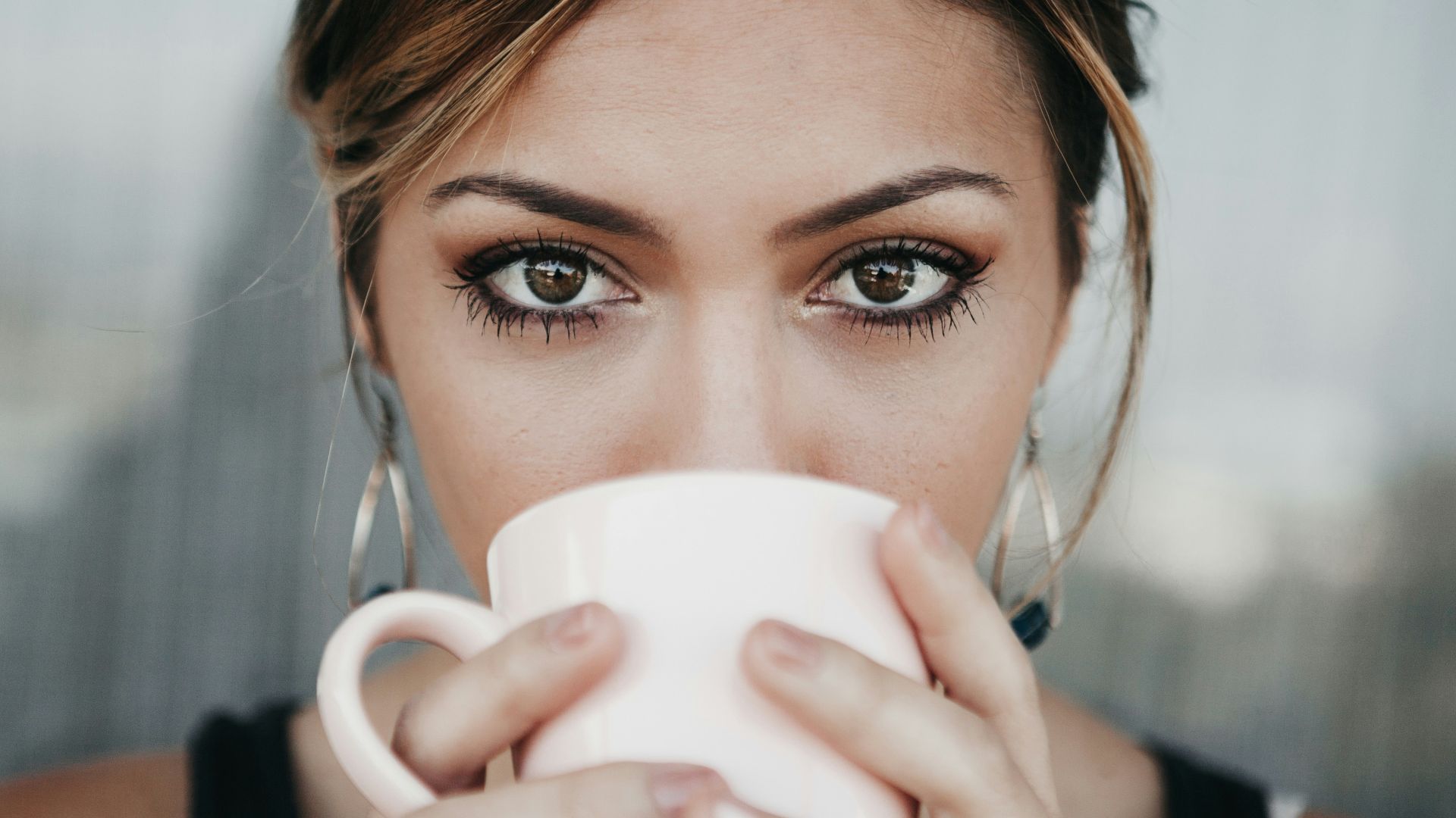 woman drinking from white coffee cup