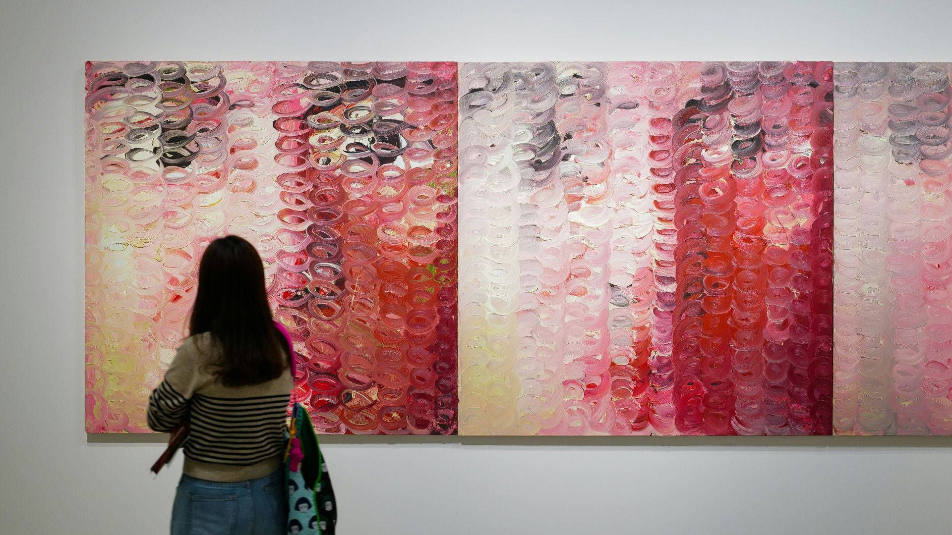 a woman standing in front of a large painting
