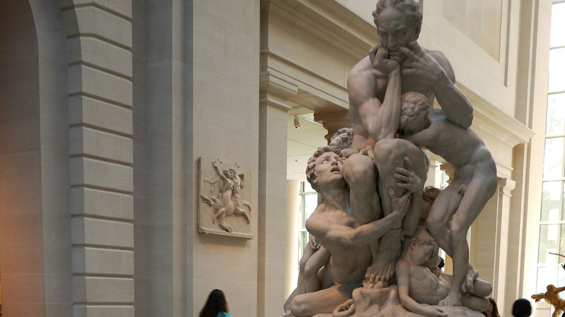 a man sitting in a chair reading a book in front of a statue