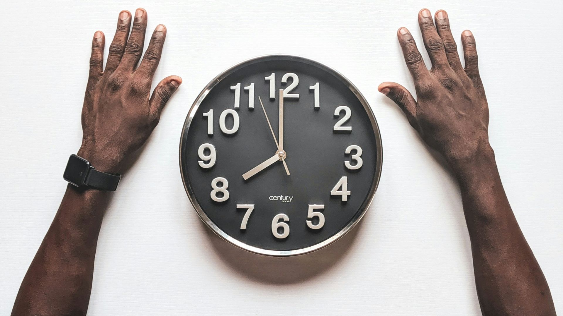 round black and white analog wall clock in front of man