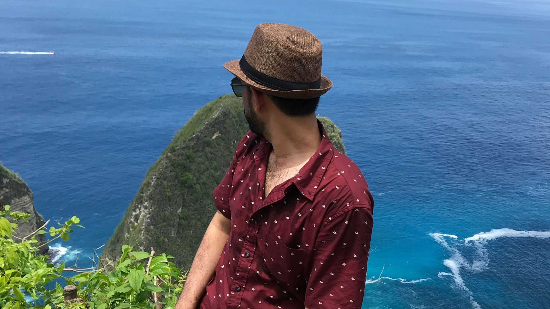 man in red dress shirt and green pants standing on green grass field near body of near near near near