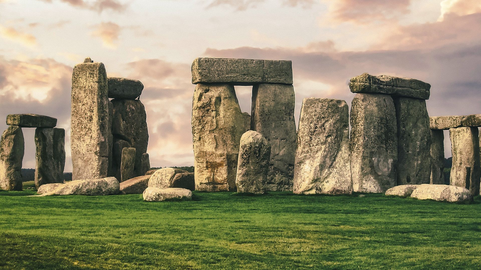 gray rock formation on green grass field under gray cloudy sky