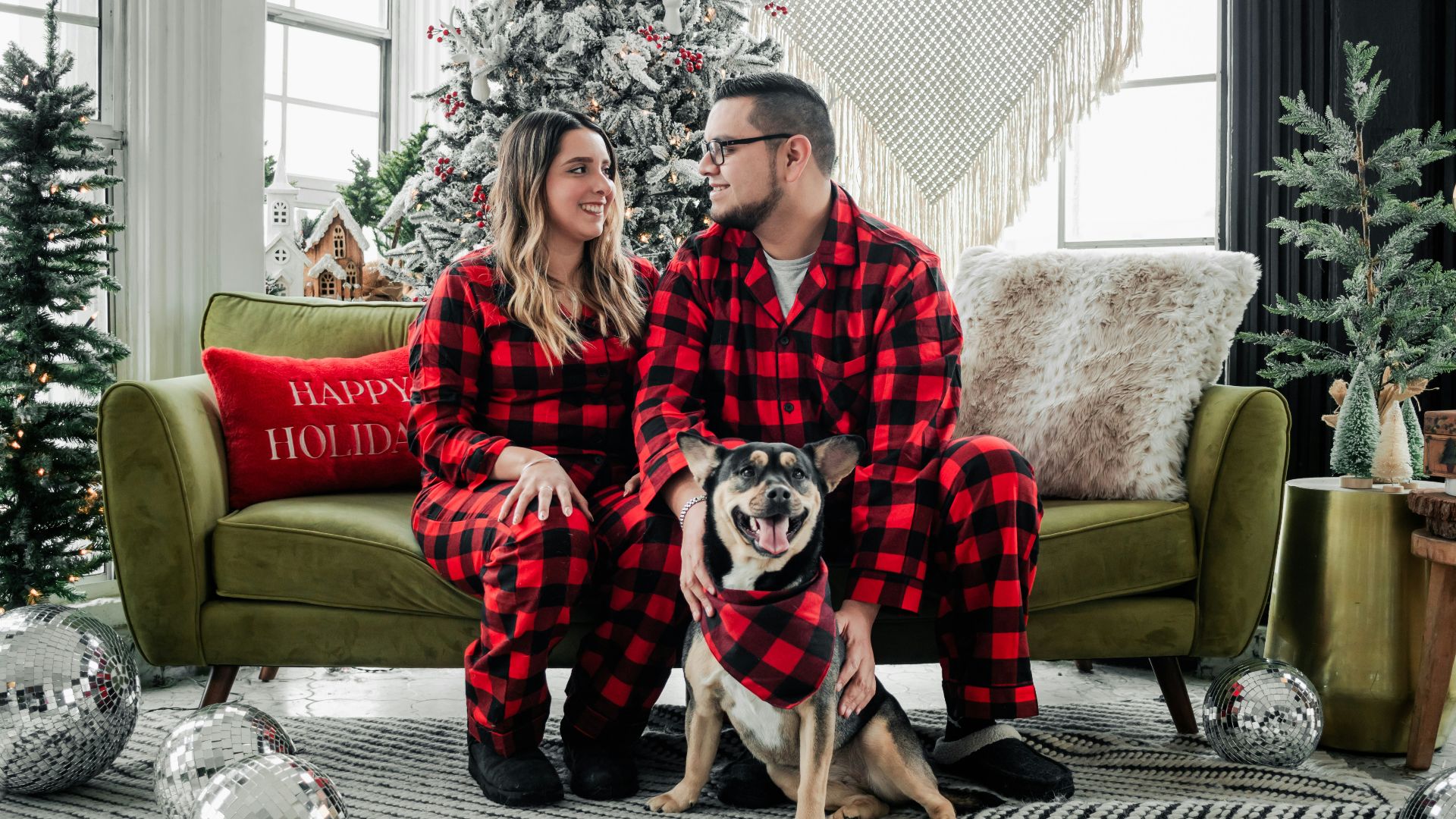 a man and woman in pajamas sitting on a couch with a dog