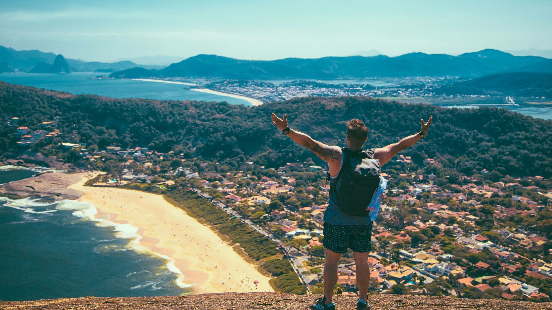 man standing front of seashore and houses