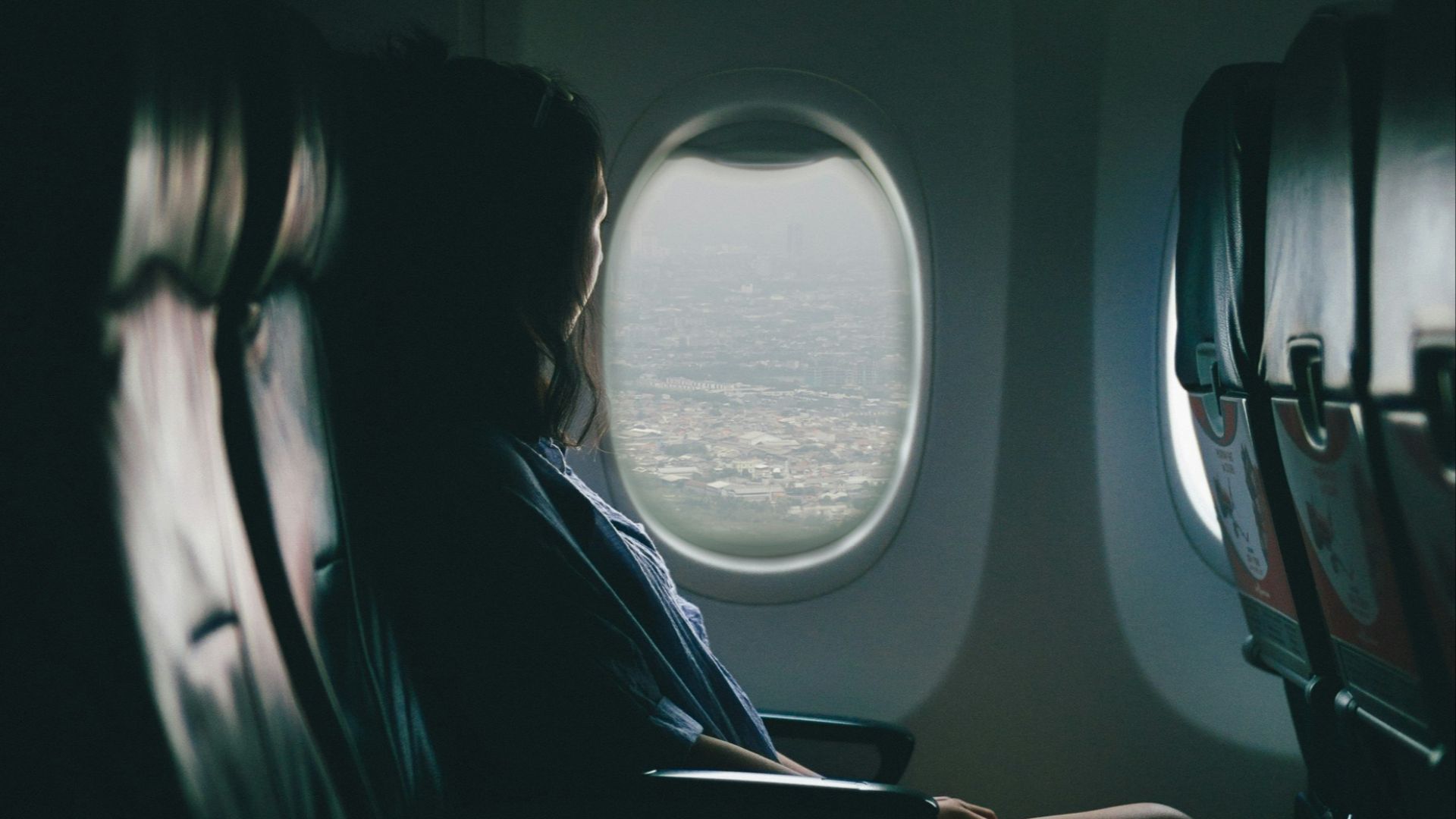 woman sits on seat near window inside plane