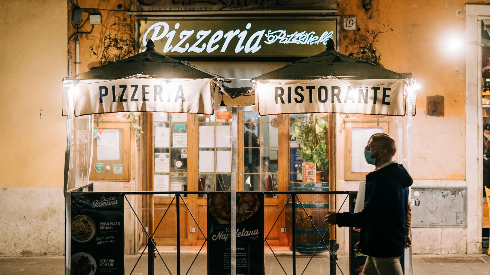 man in black jacket and black pants standing in front of brown wooden store during daytime