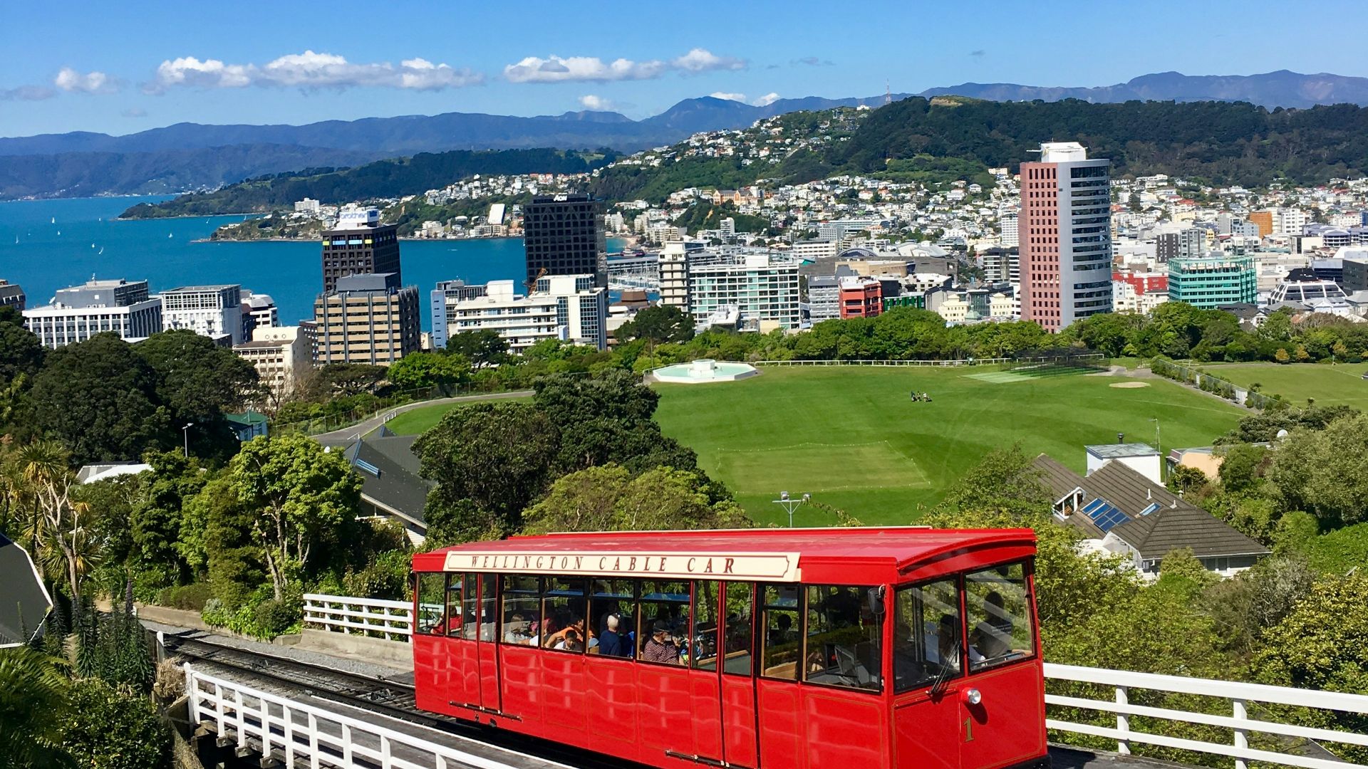 red train on rail with cityscape view underlue sky