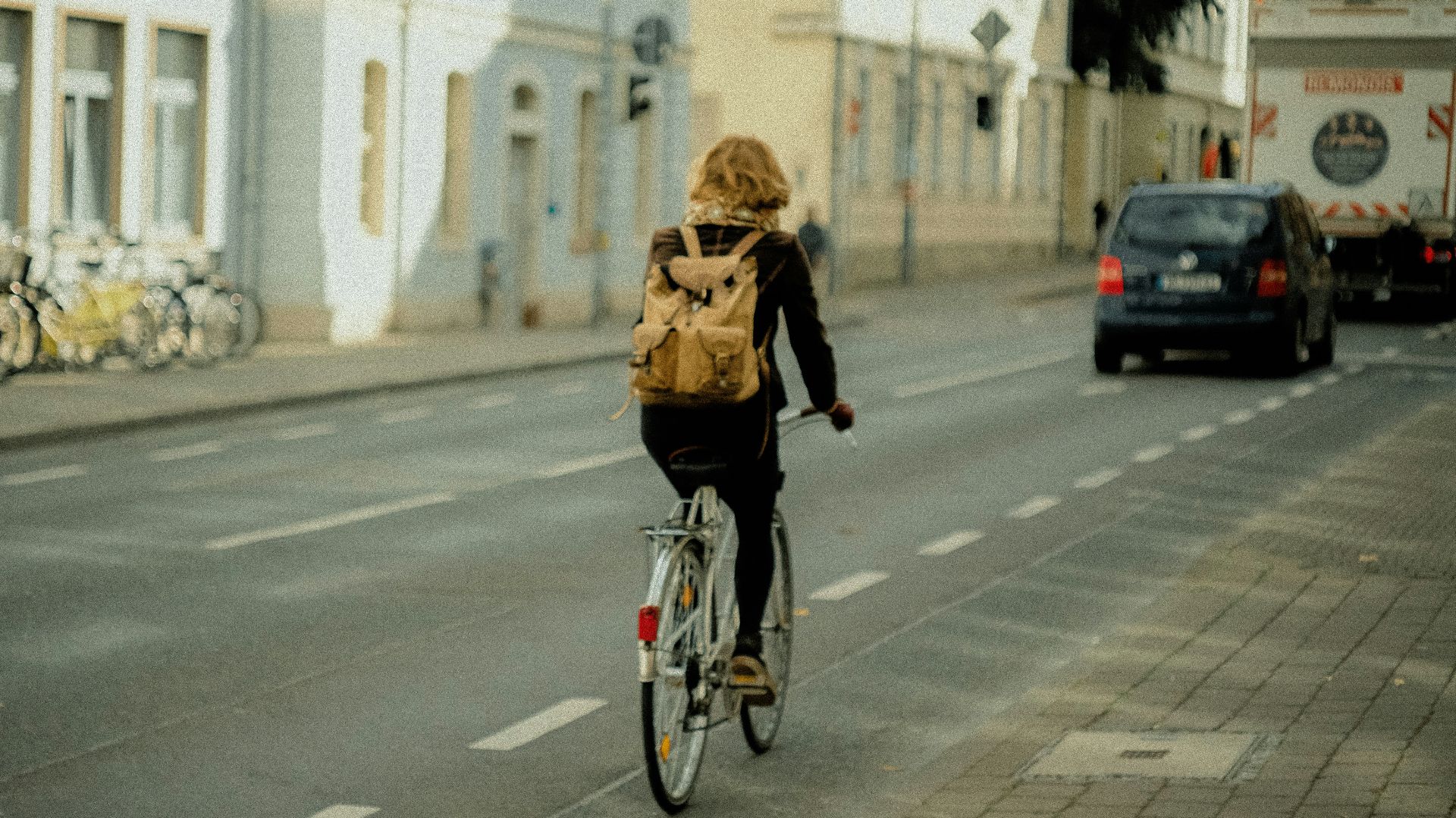 woman in black jacket riding bicycle on road during daytime