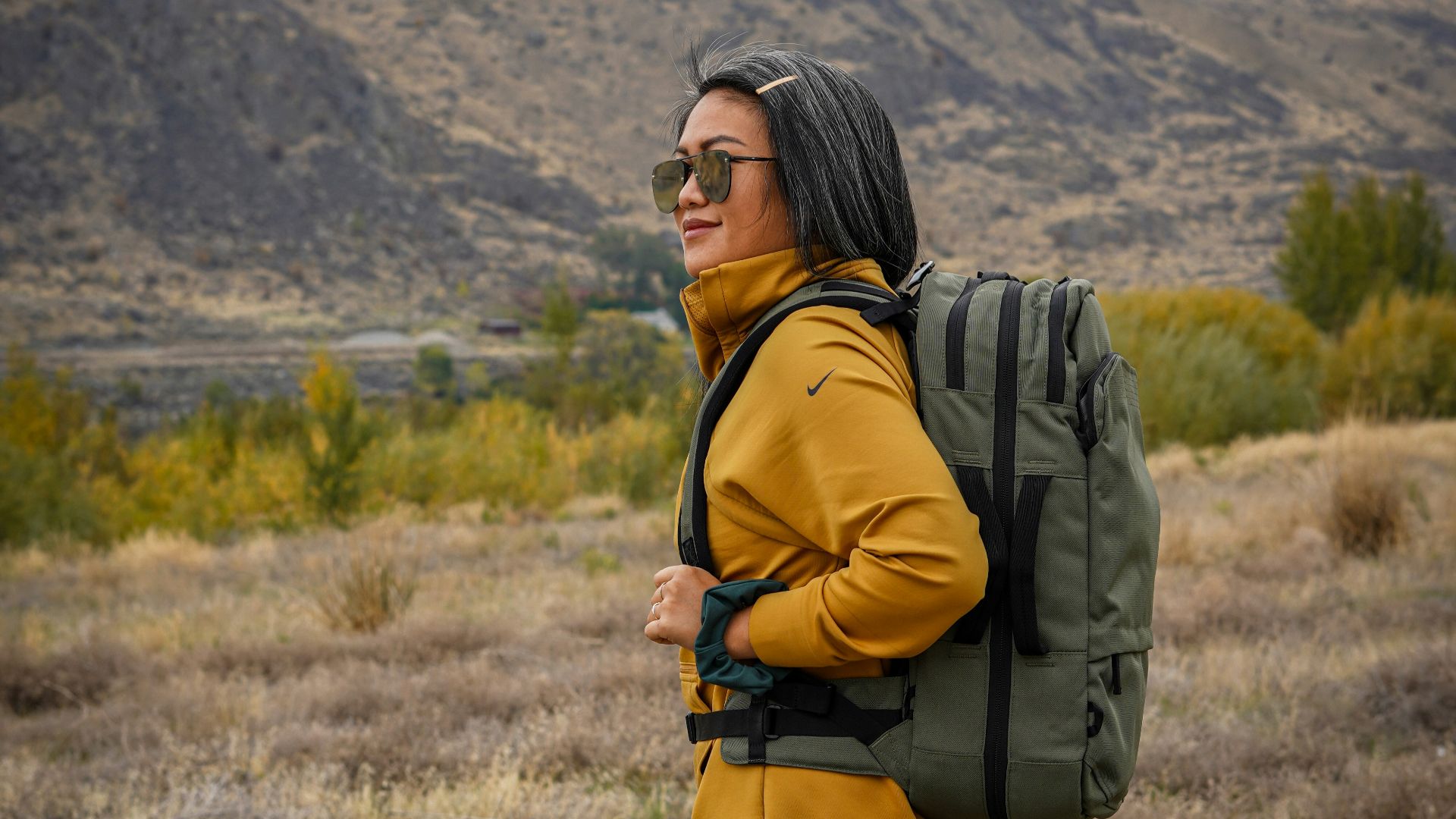 woman in black and white plaid skirt with black backpack standing on green grass field during