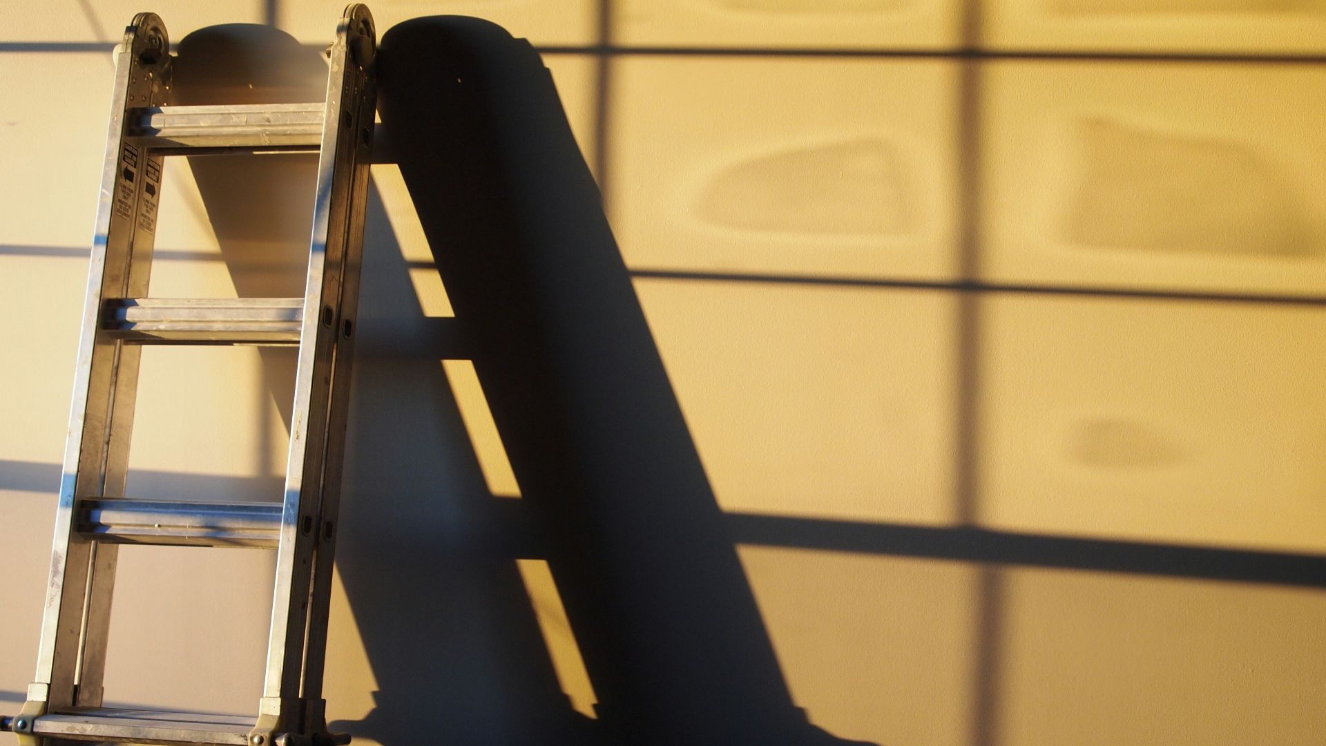 black metal ladder leaning on white wall