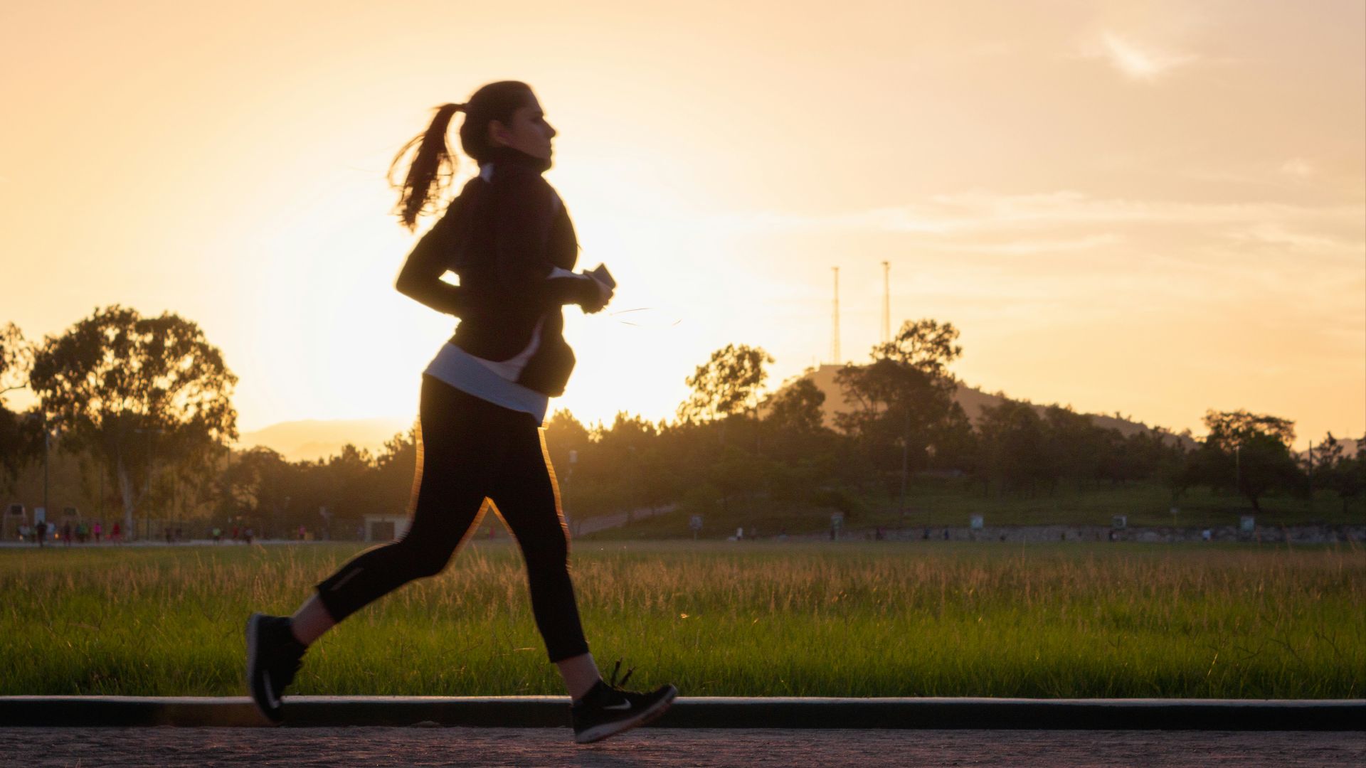 woman in black sports bra and black pants running on water during sunset