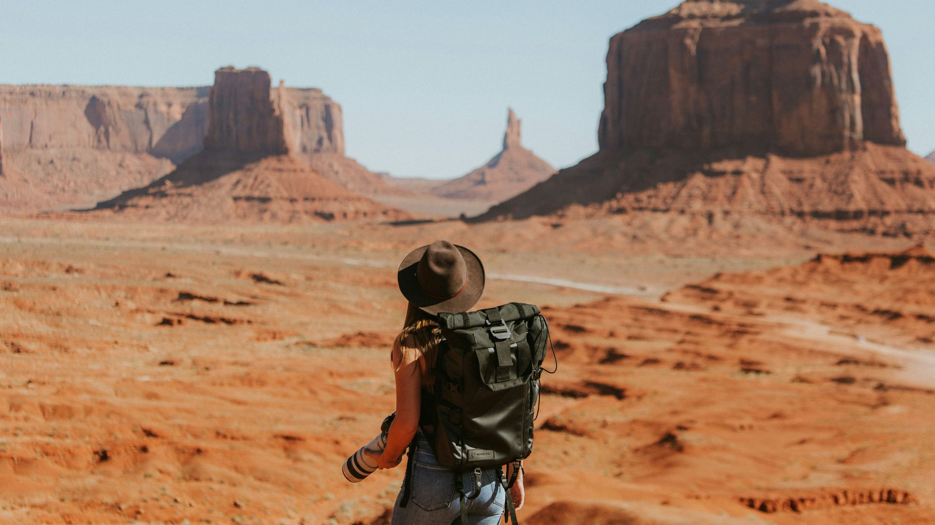 woman with black backpack standing on brown dessert