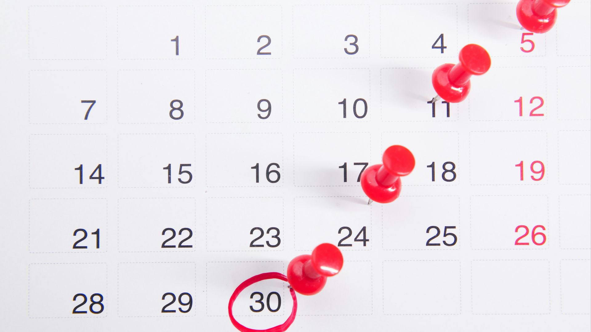 a calendar with red push buttons pinned to it