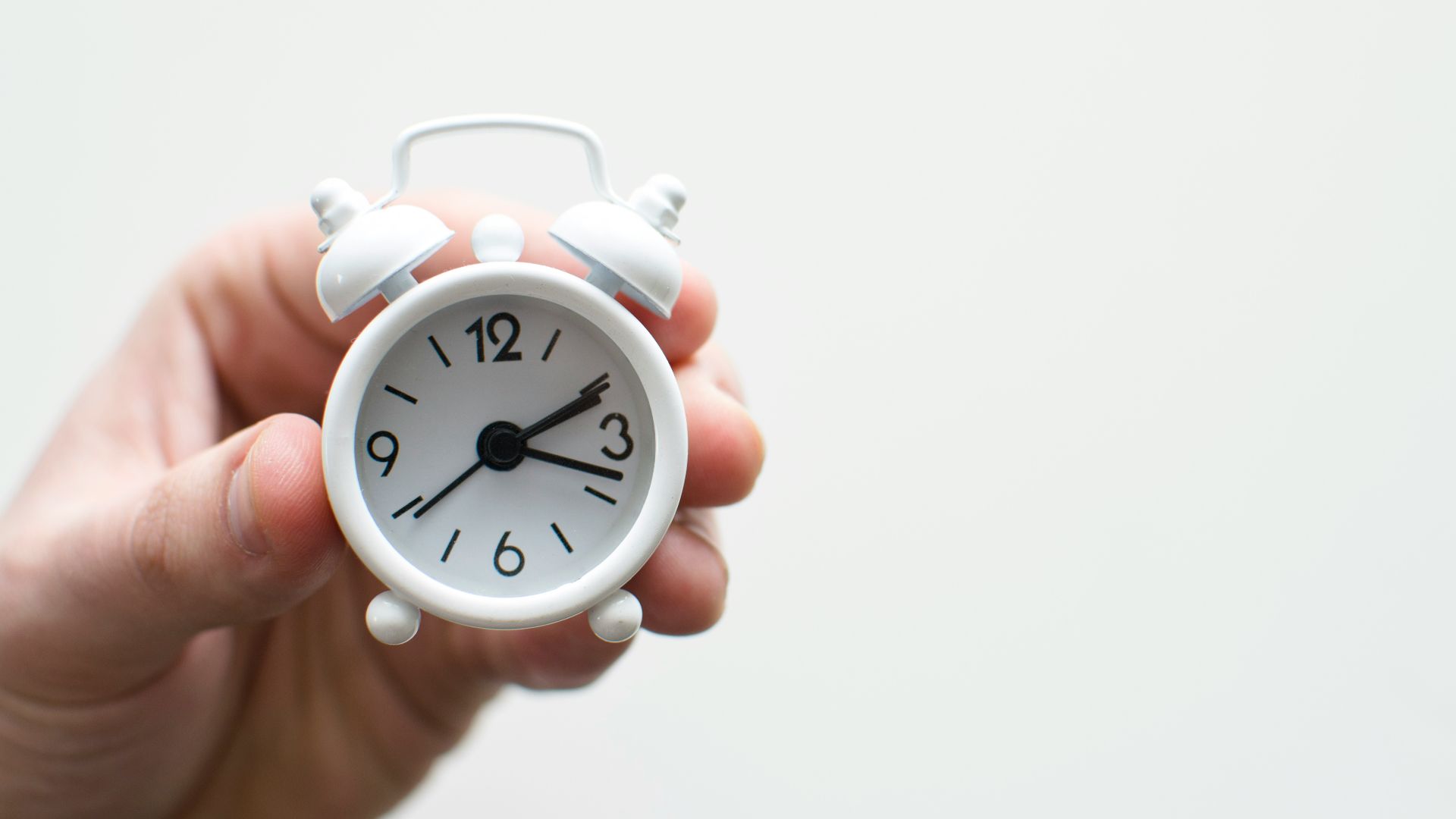 person holding white mini bell alarmclock